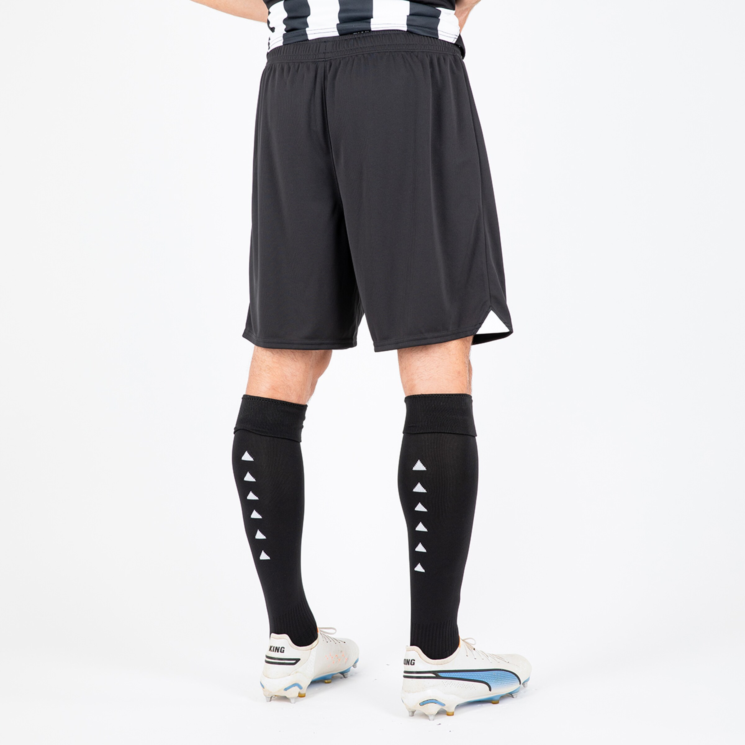 Ein Spieler von hinten in schwarzen Fußballshorts und langen Socken mit Pfeilmuster.