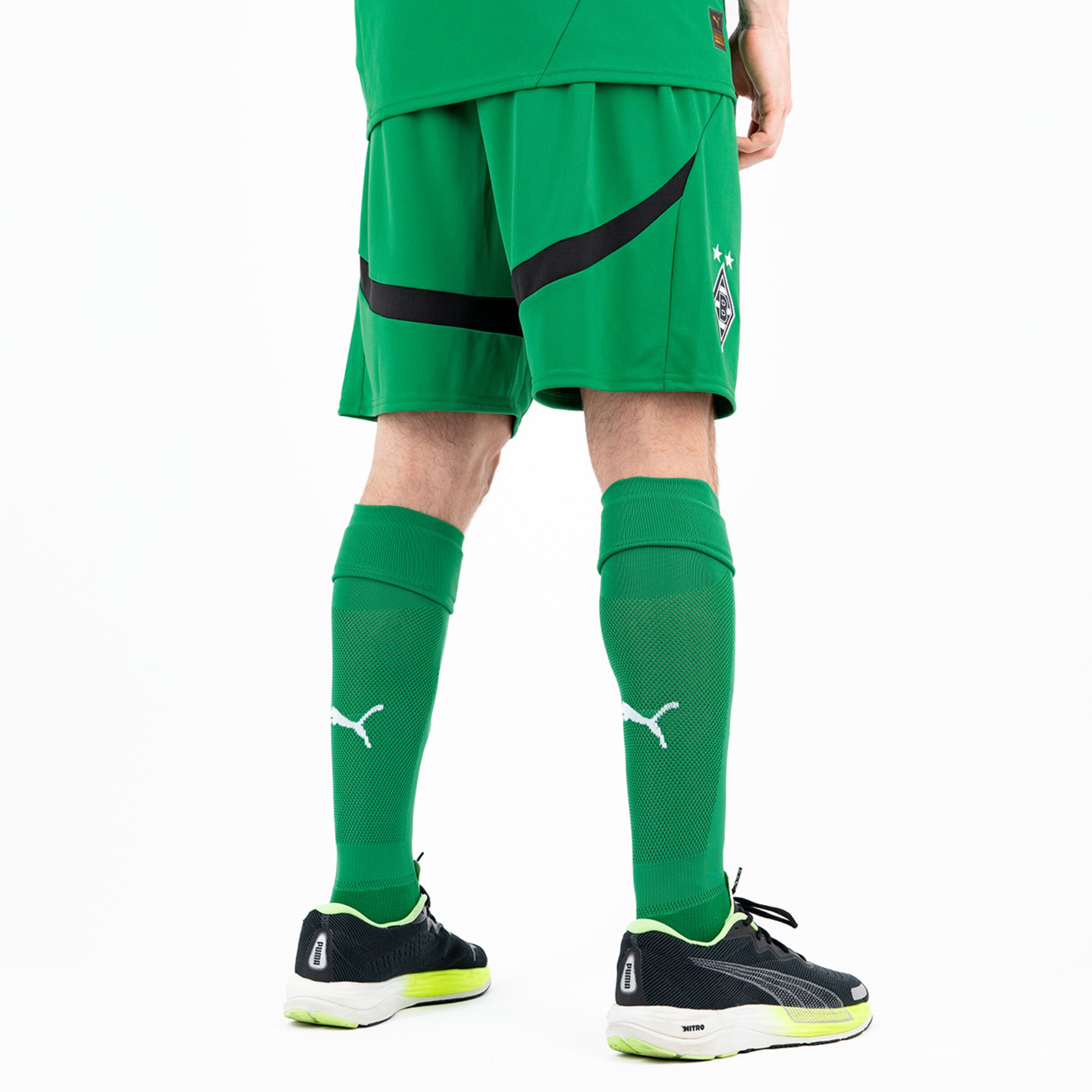 Torwarttrikot und grüne Shorts mit langen Socken im Hintergrund seitliche Ansicht.