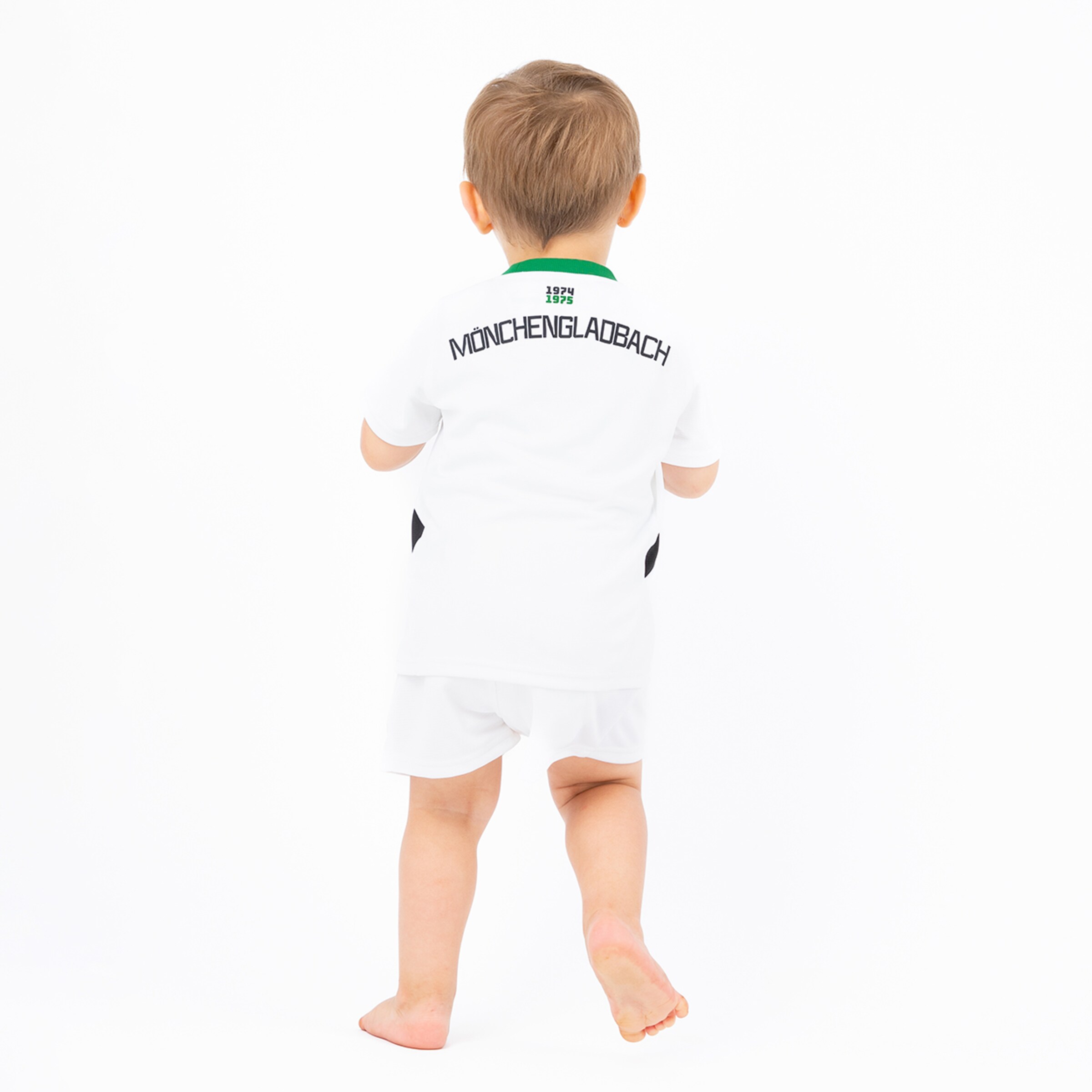 Ein Kleinkind trägt ein weißes Borussia Mönchengladbach Trikot sieht von hinten.