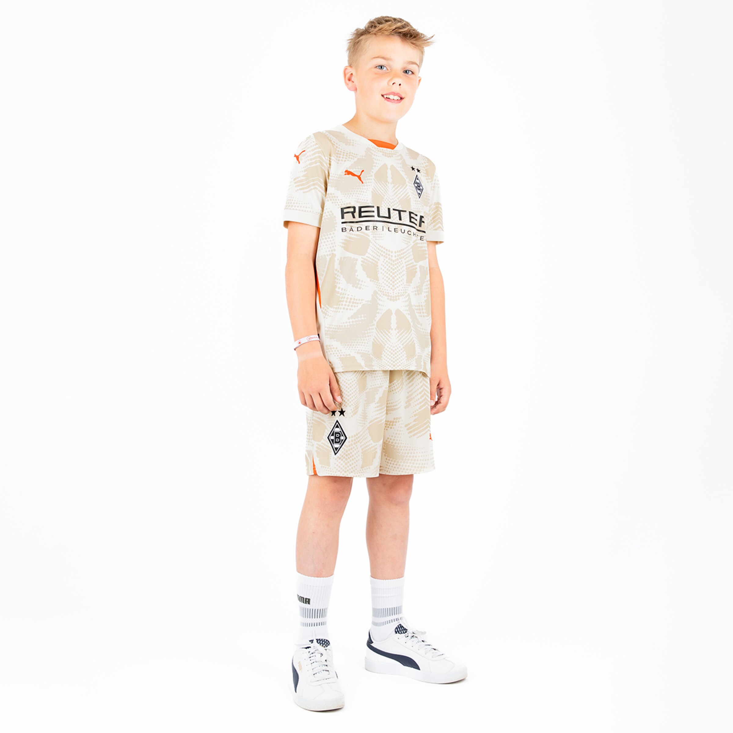 Junge in beigem Fußballtrikot und Shorts mit Puma-Logo und Borussia Mönchengladbach Schriftzug.
