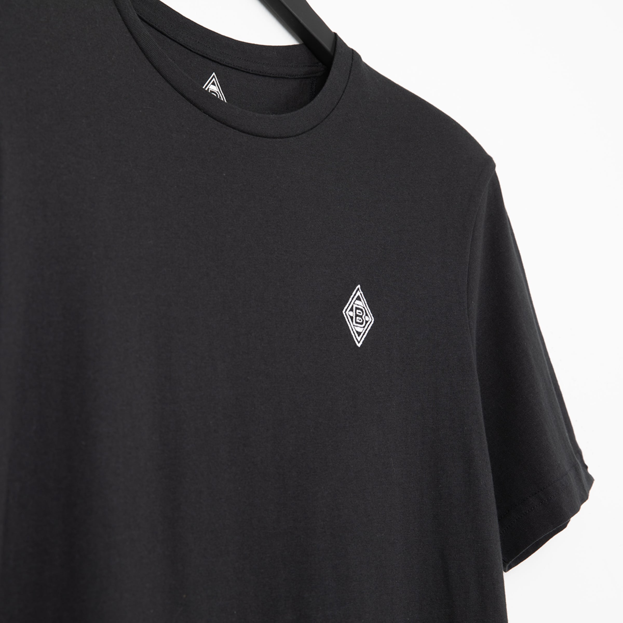 Schwarzes T-Shirt mit dem Borussia Mönchengladbach-Logo auf der linken Brustseite.