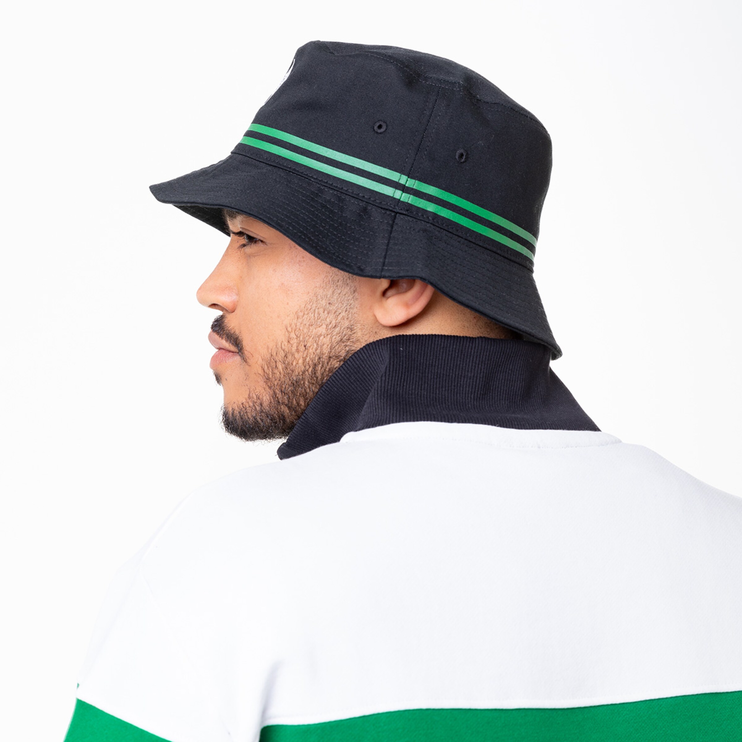 Mann mit schwarzem Bucket Hat und gestreifter Kante trägt ein weißes Polo mit grünen Streifen.