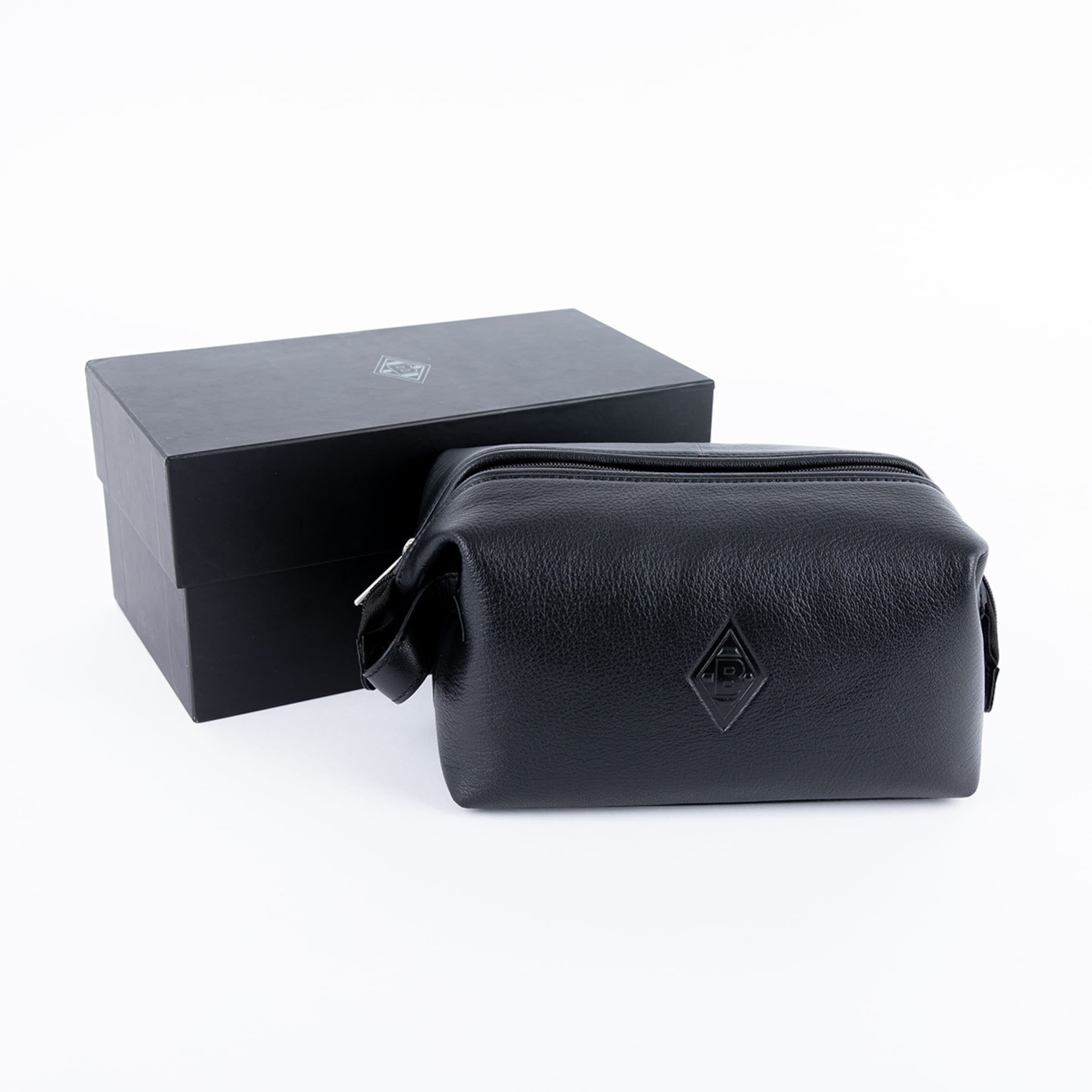 Schwarzer Kulturbeutel aus genarbtem Leder neben einer schwarzen Geschenkbox, beide mit Rauten-Logo.