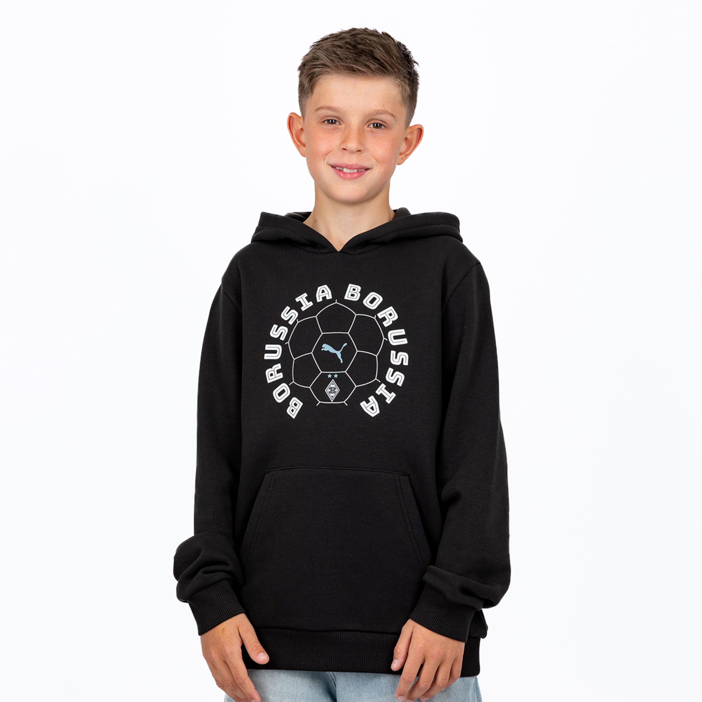 Ein lächelnder Junge in einem schwarzen Hoodie mit einer weißen, runden Grafik, die einen Fußball, den Schriftzug „BORUSSIA“, das hellblaue Puma-Logo und das Borussia Mönchengladbach-Logo zeigt, steht vor einem weißen Hintergrund.