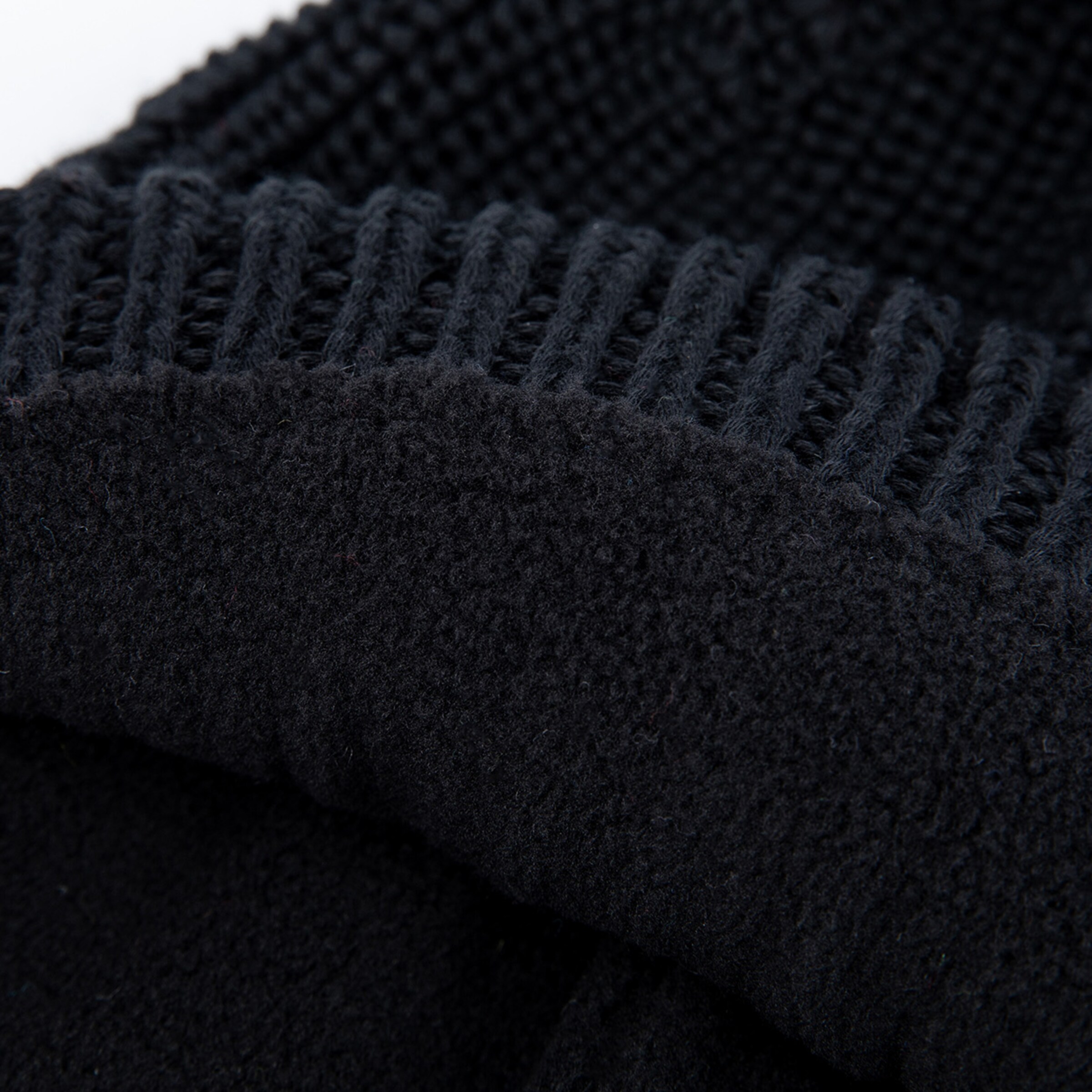 Close-up of black fabric with a knitted pattern and fleece lining