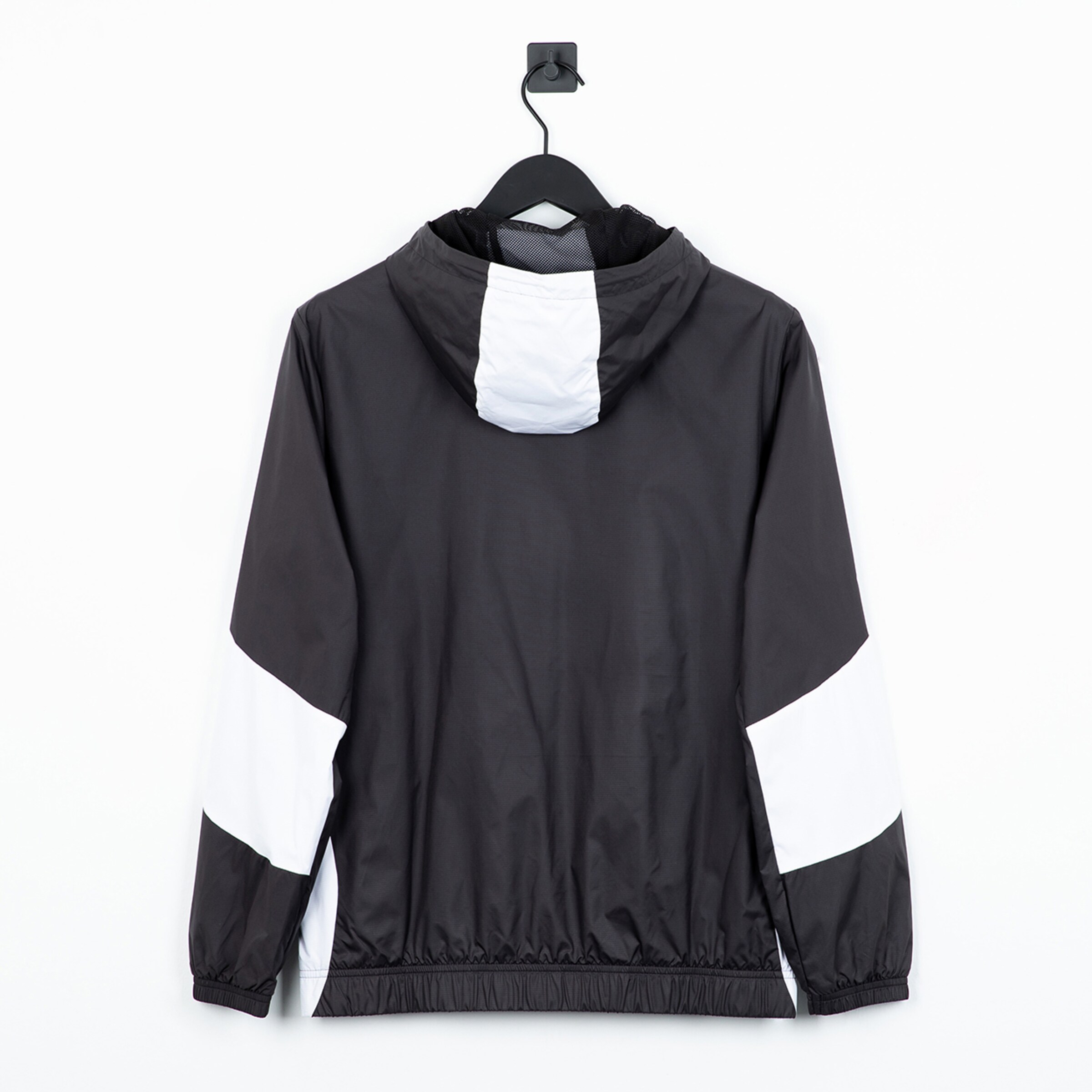 Rückansicht einer schwarzen Jacke mit weißen Akzenten an einem Haken aufgehängt.