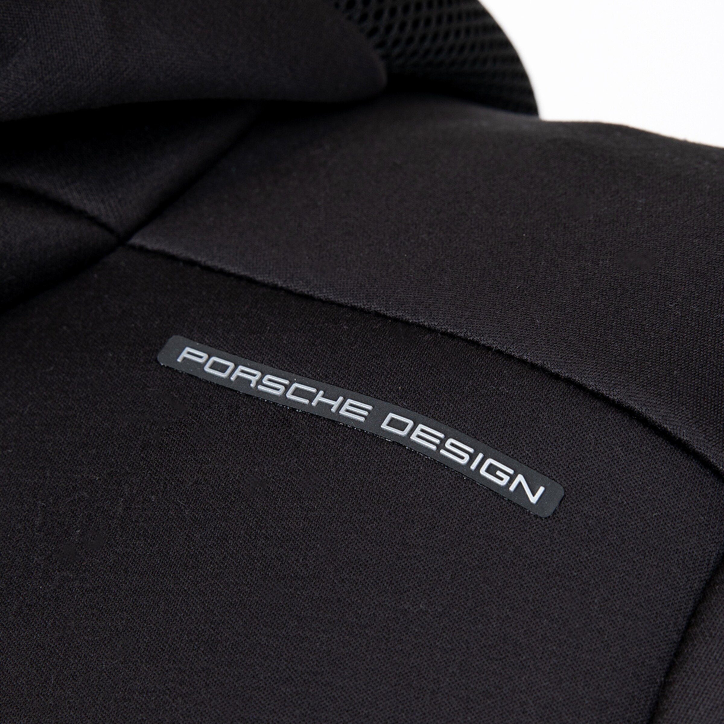 Porsche Design-Logo auf dunkler Textiloberfläche.