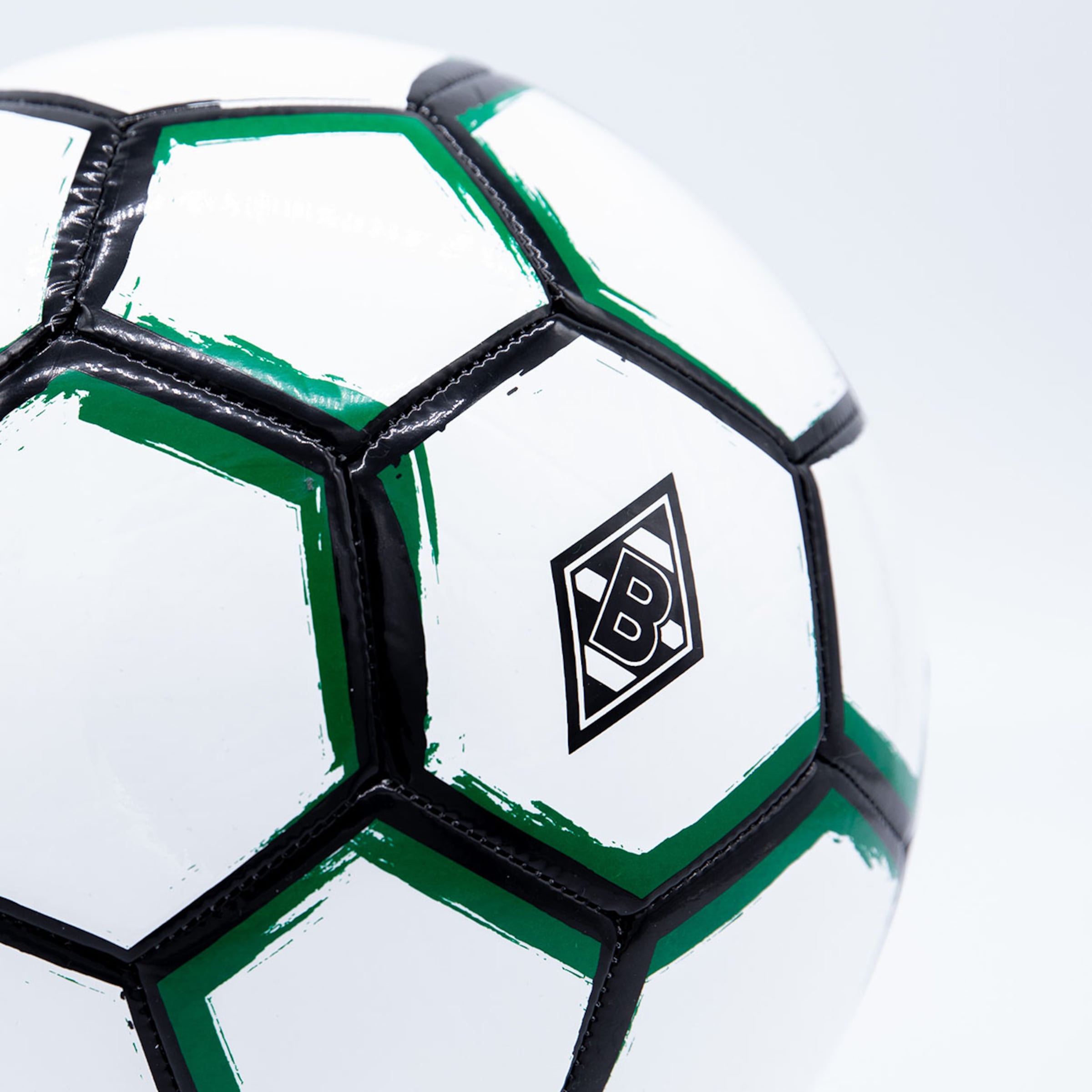 Nahaufnahme eines weiß-grünen Fußballs mit dem Rauten-Logo von Borussia Mönchengladbach auf weißem Hintergrund.