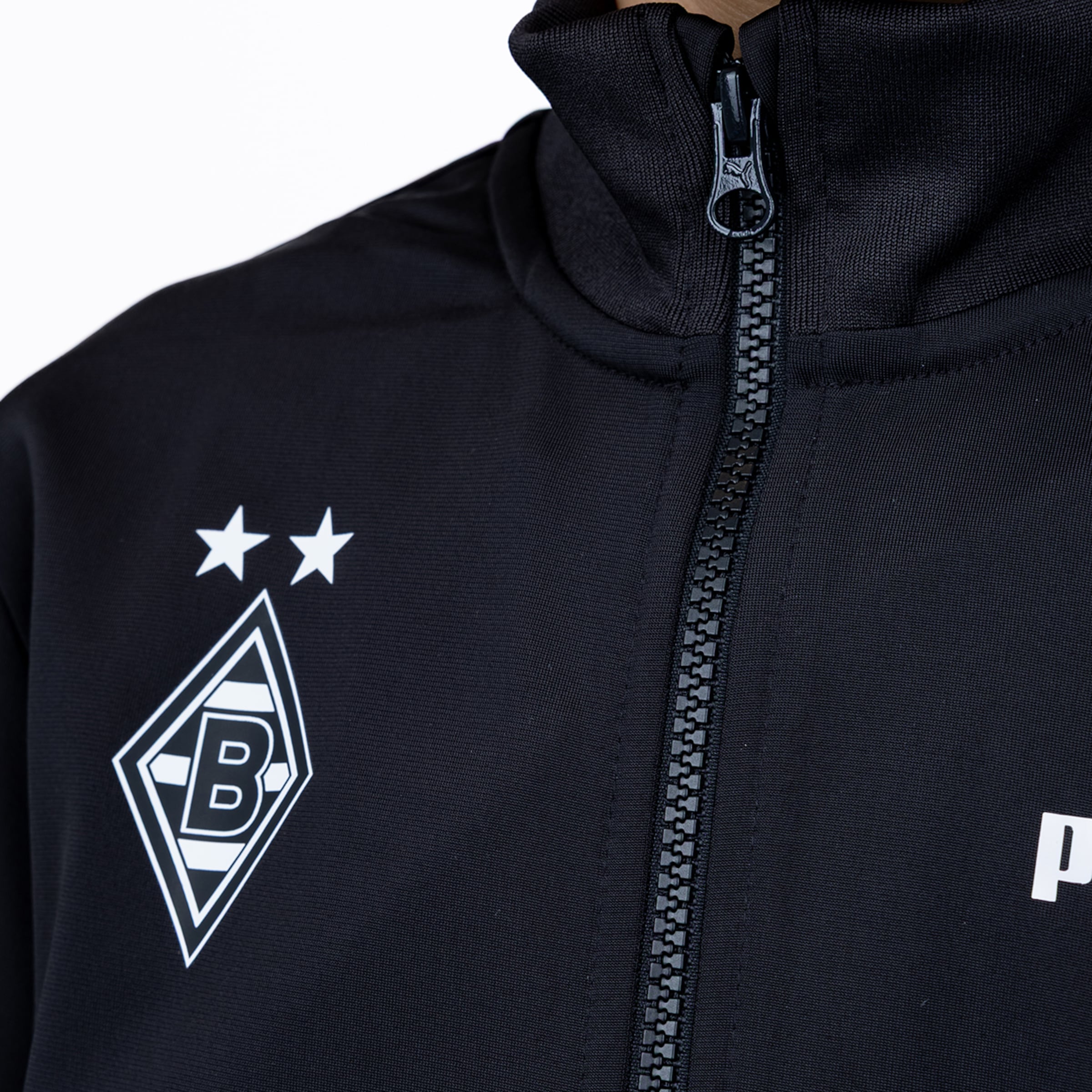 Close-up of a black Puma Borussia Mönchengladbach track jacket showing the club crest, two stars, and a zipper.