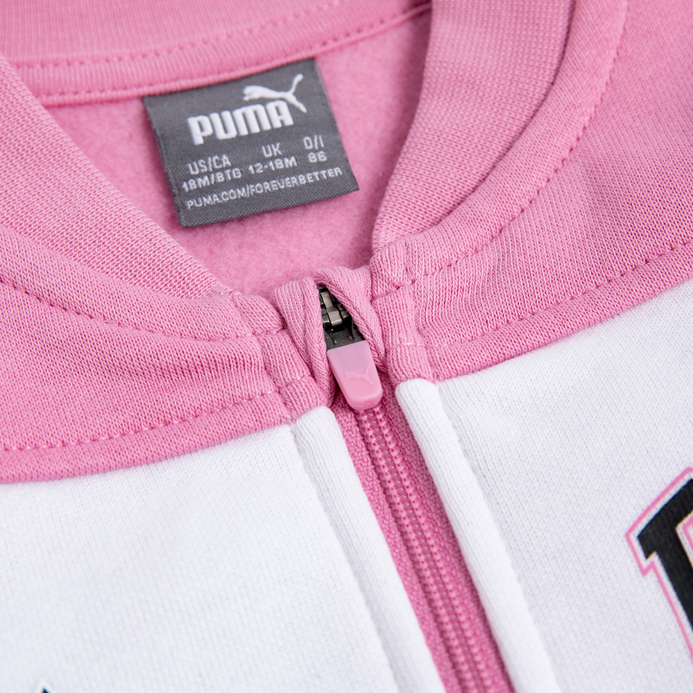 Close-up of a pink Puma zipper on a white sweatshirt.