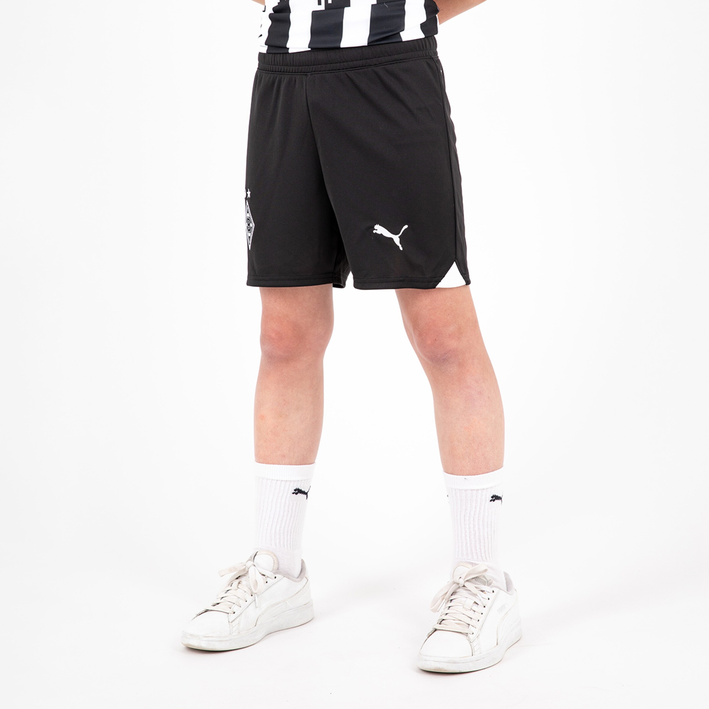 Black soccer shorts with white Puma logos worn by a youth.
