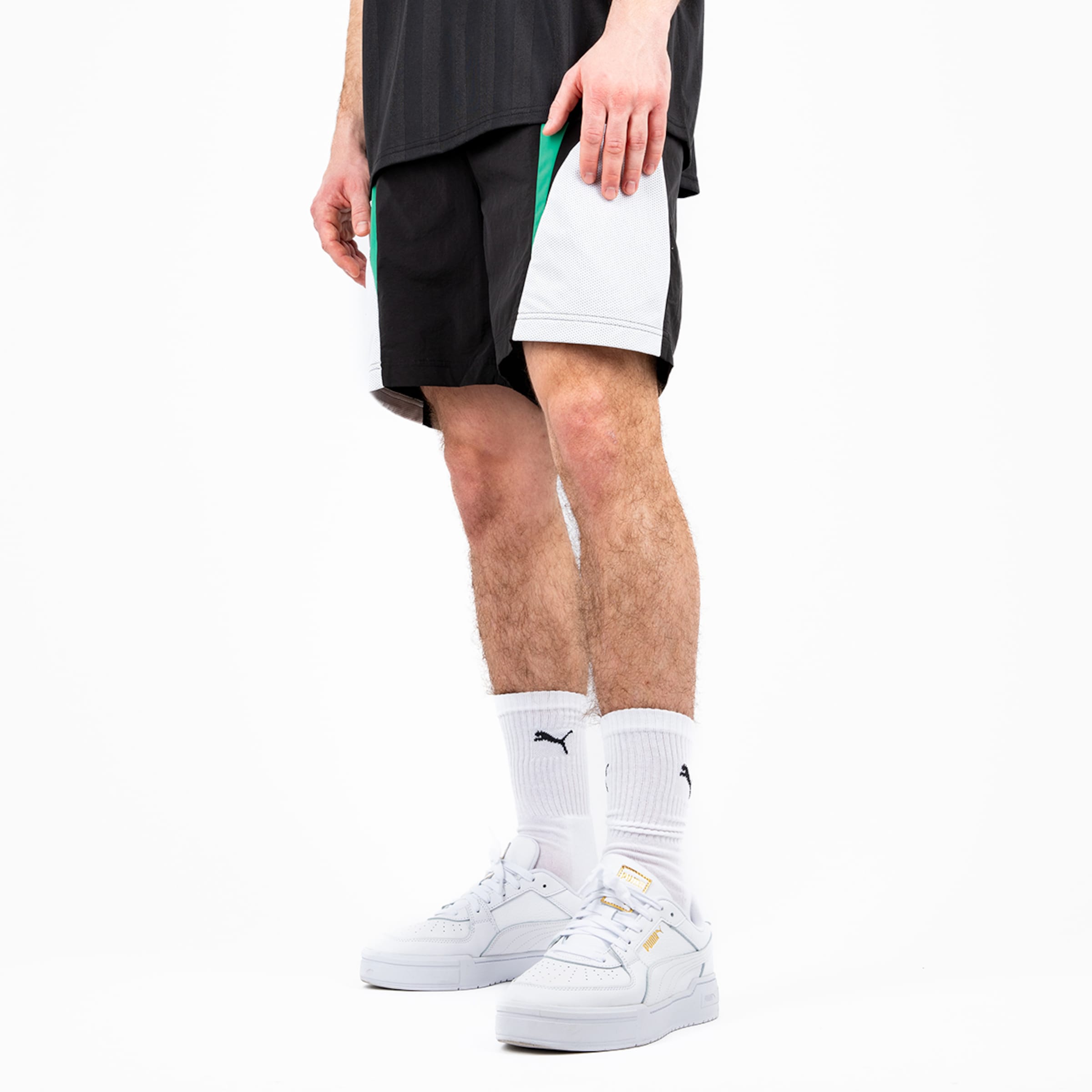 Person trägt sportliche Shorts in Schwarz und Weiß und Sneakers von Puma.