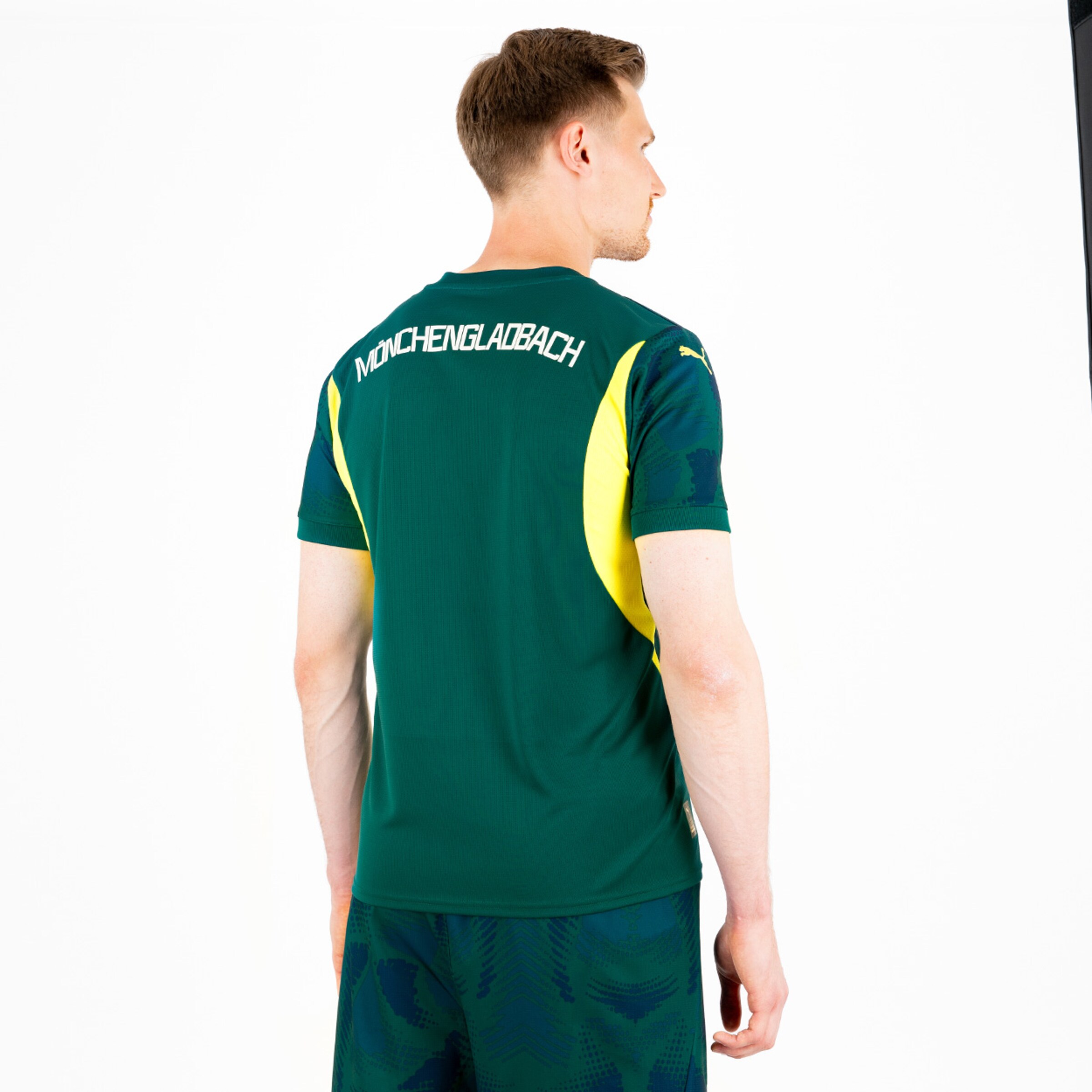 Ein Spieler steht von hinten in einem Trikot von Borussia Mönchengladbach in grün mit gelben Details.