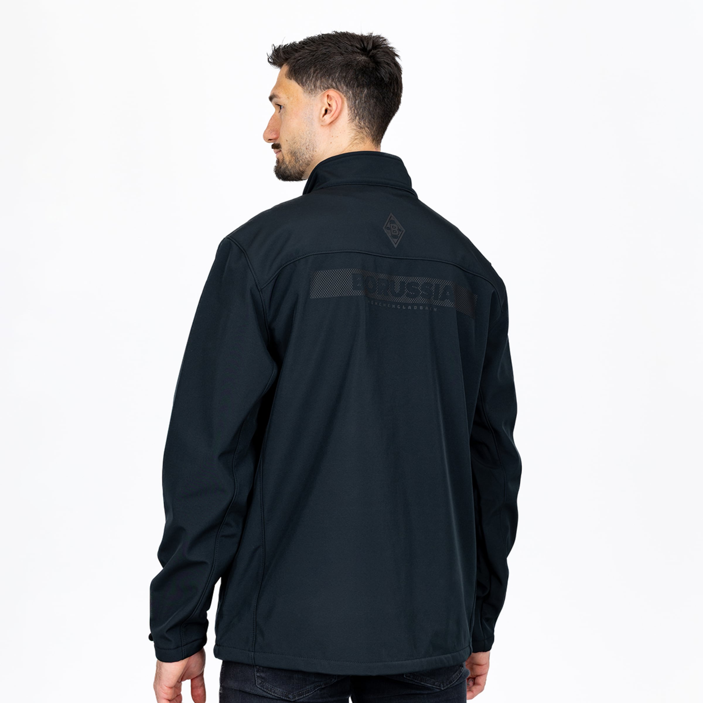 Rückansicht eines Mannes in schwarzer Softshelljacke mit dezentem „BORUSSIA“-Schriftzug und Logo auf dem Rücken. Weißer Hintergrund.