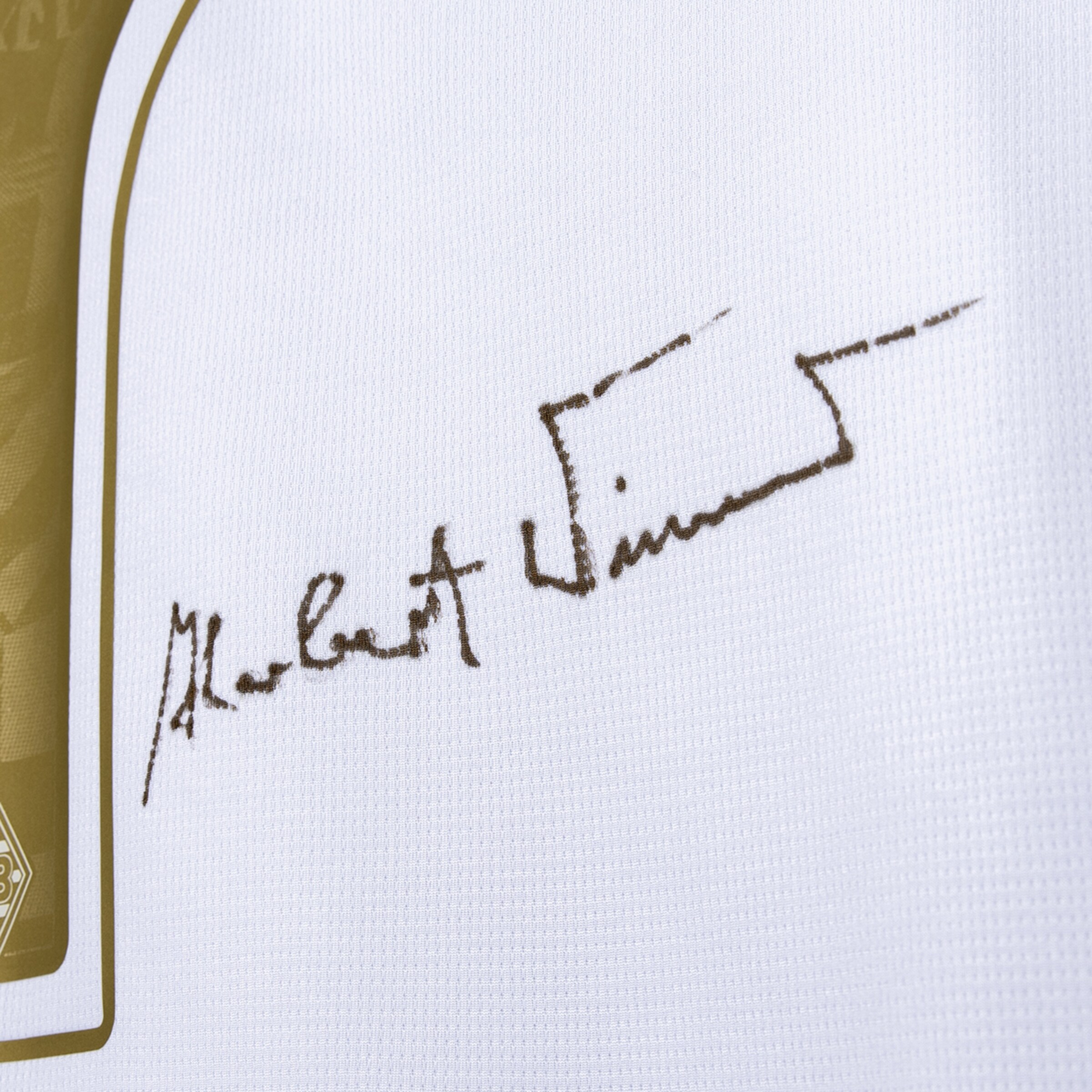 Nahaufnahme der Signatur von Herbert Wimmer auf weißem Trikotstoff.