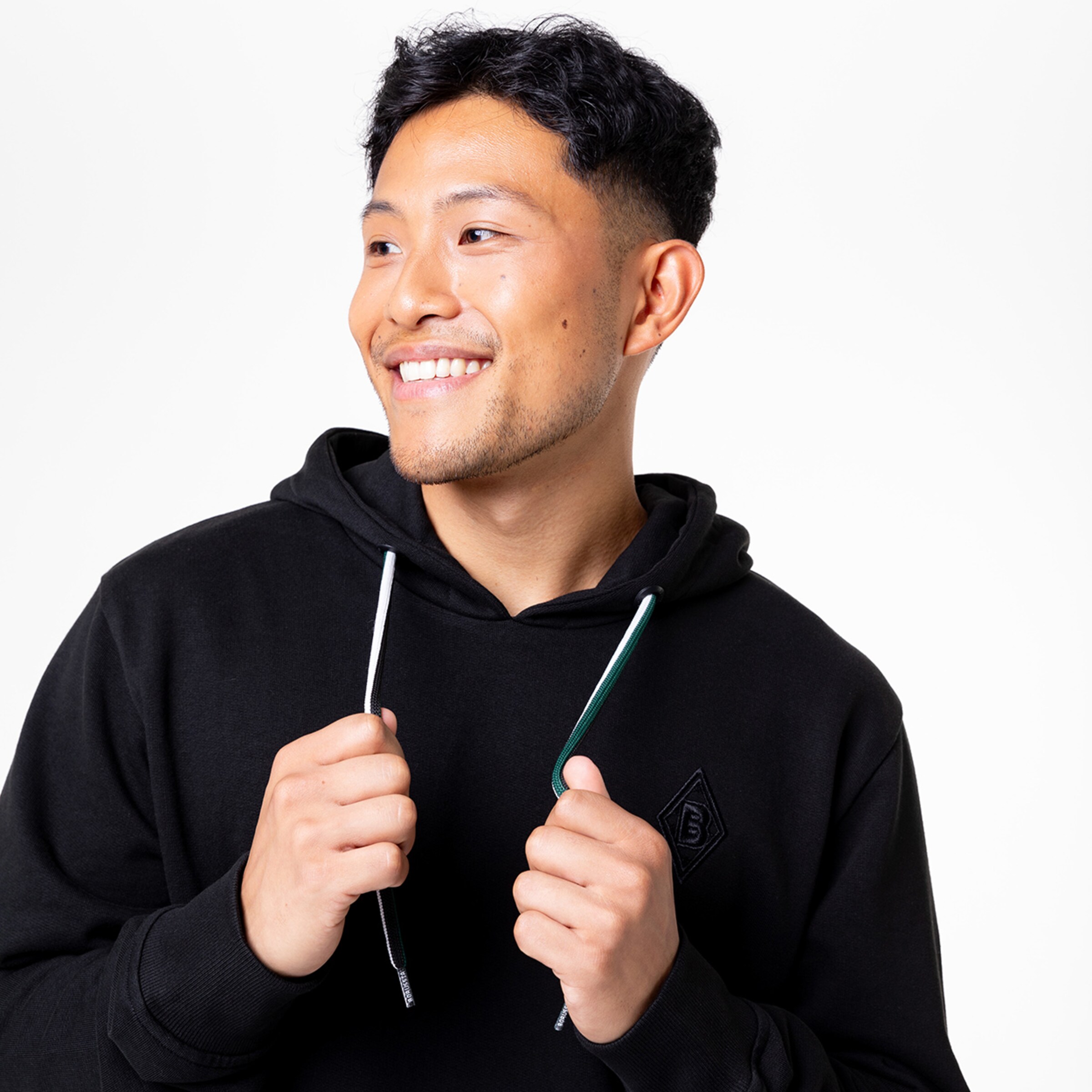 Mann in schwarzer Kapuzenjacke lächelt hält zwei Kabel in der Hand.