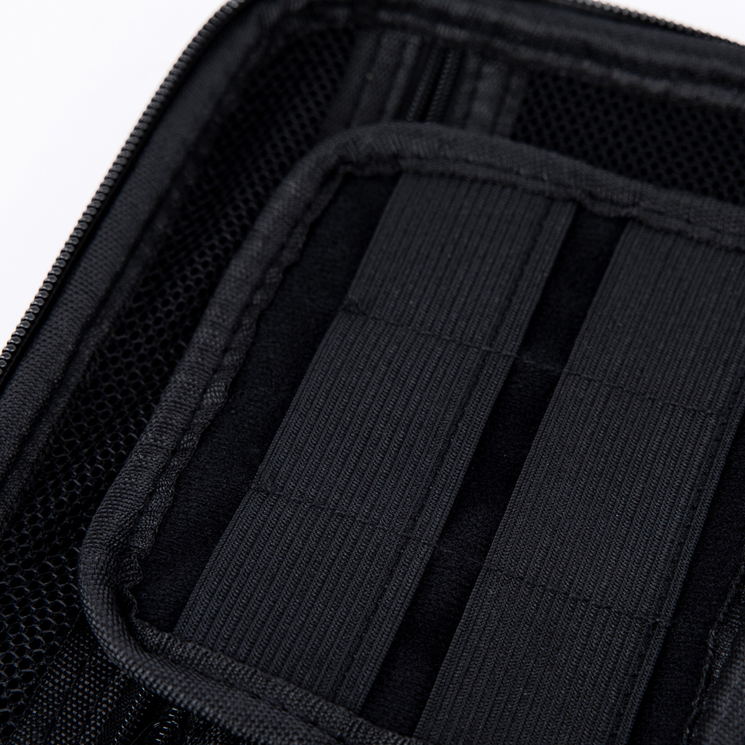 Nahaufnahme des Innenraums einer schwarzen Tasche mit elastischen Schlaufen und Netzfächern.
