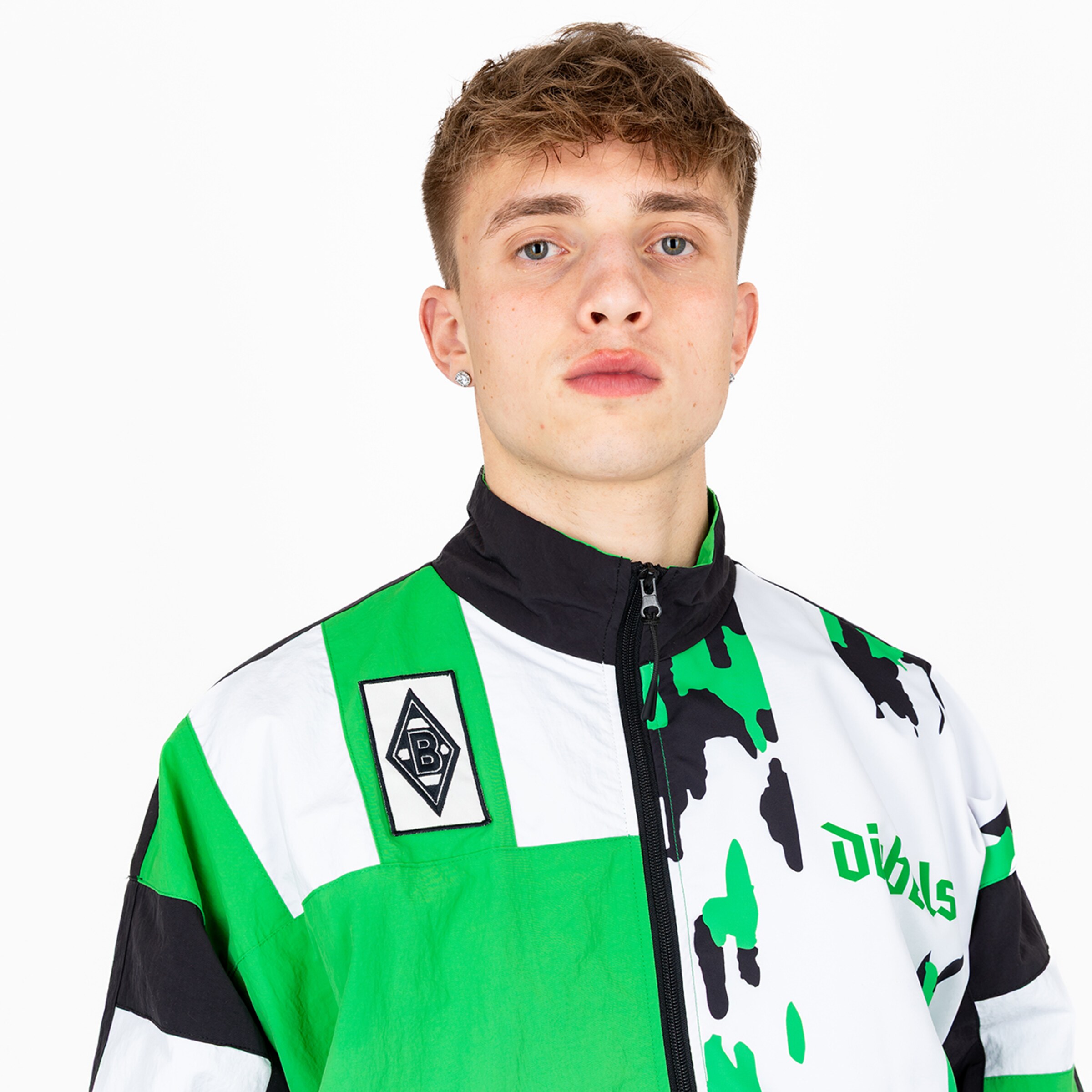 A young man with short blond hair wearing a green and white Borussia Mönchengladbach training jacket.