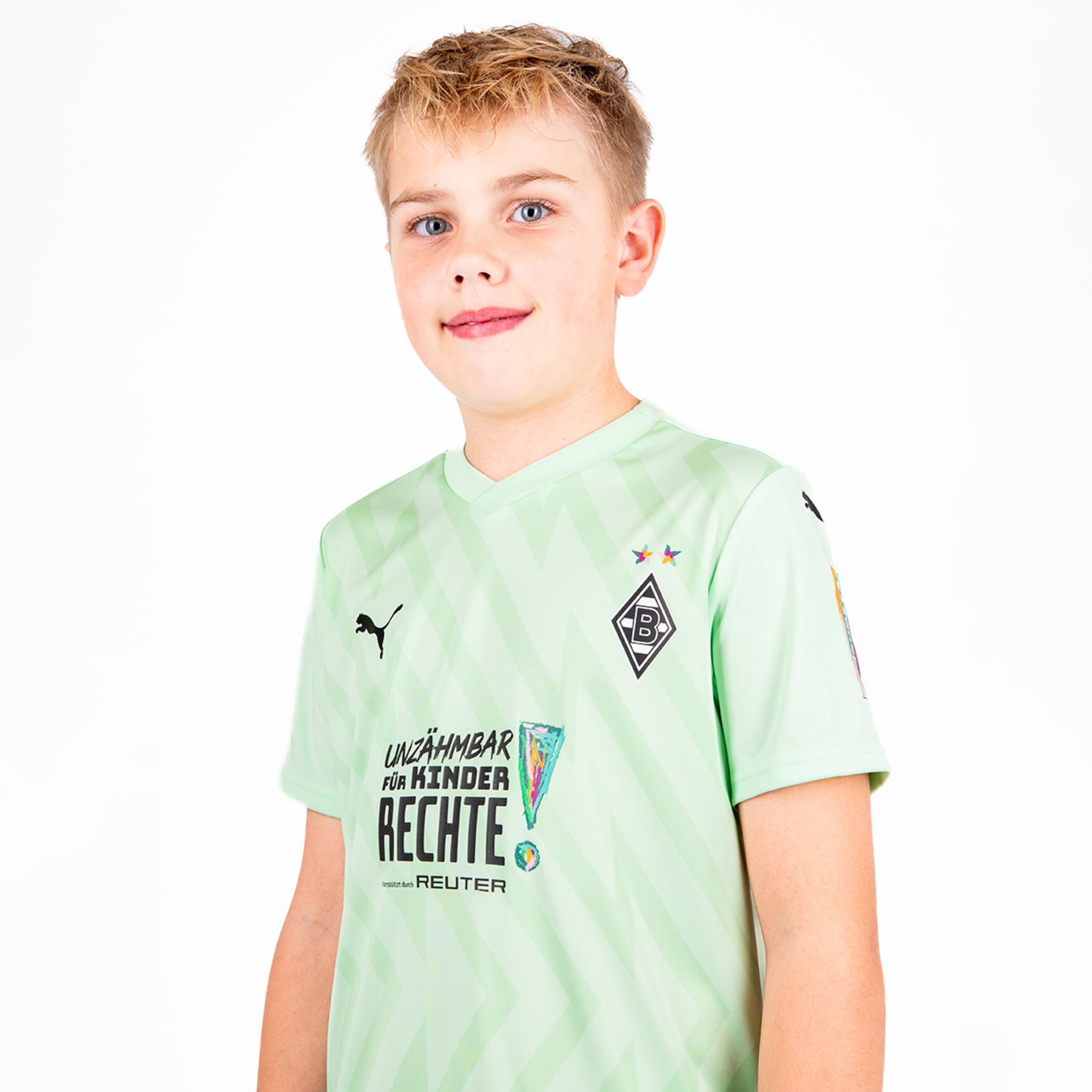 Ein Junge trägt das grüne Trikot von Borussia Mönchengladbach mit dem Schriftzug Unzähmbar für Kinder Rechte.