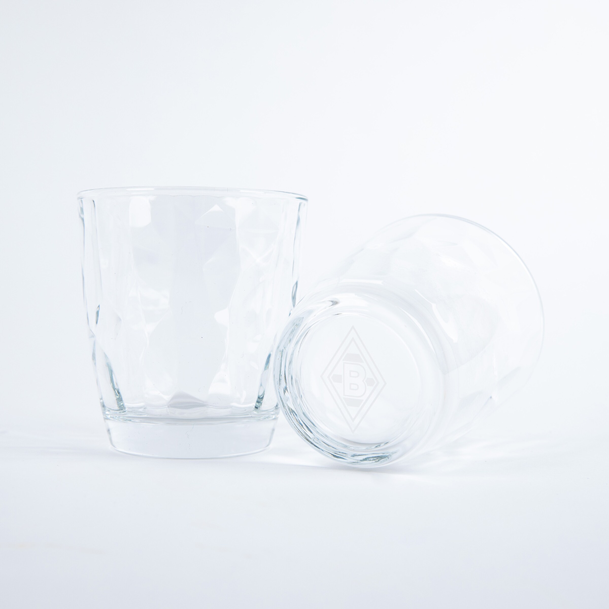 Zwei klare Trinkgläser mit dem Borussia Mönchengladbach-Logo eines aufrecht das andere gekippt.