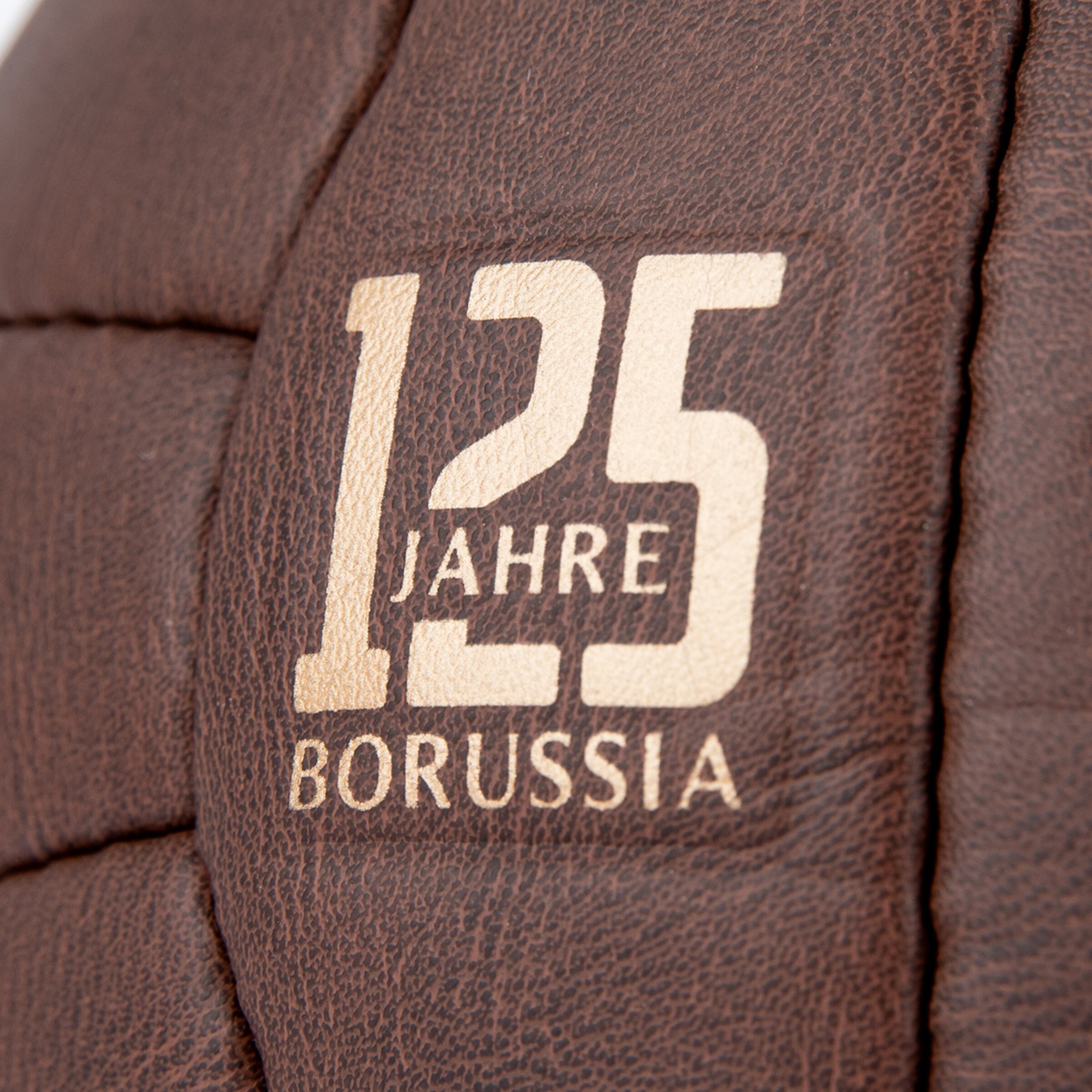 Nahaufnahme eines braunen Leder-Fußballs mit goldenem Aufdruck „125 JAHRE BORUSSIA“ zum 125. Jubiläum.