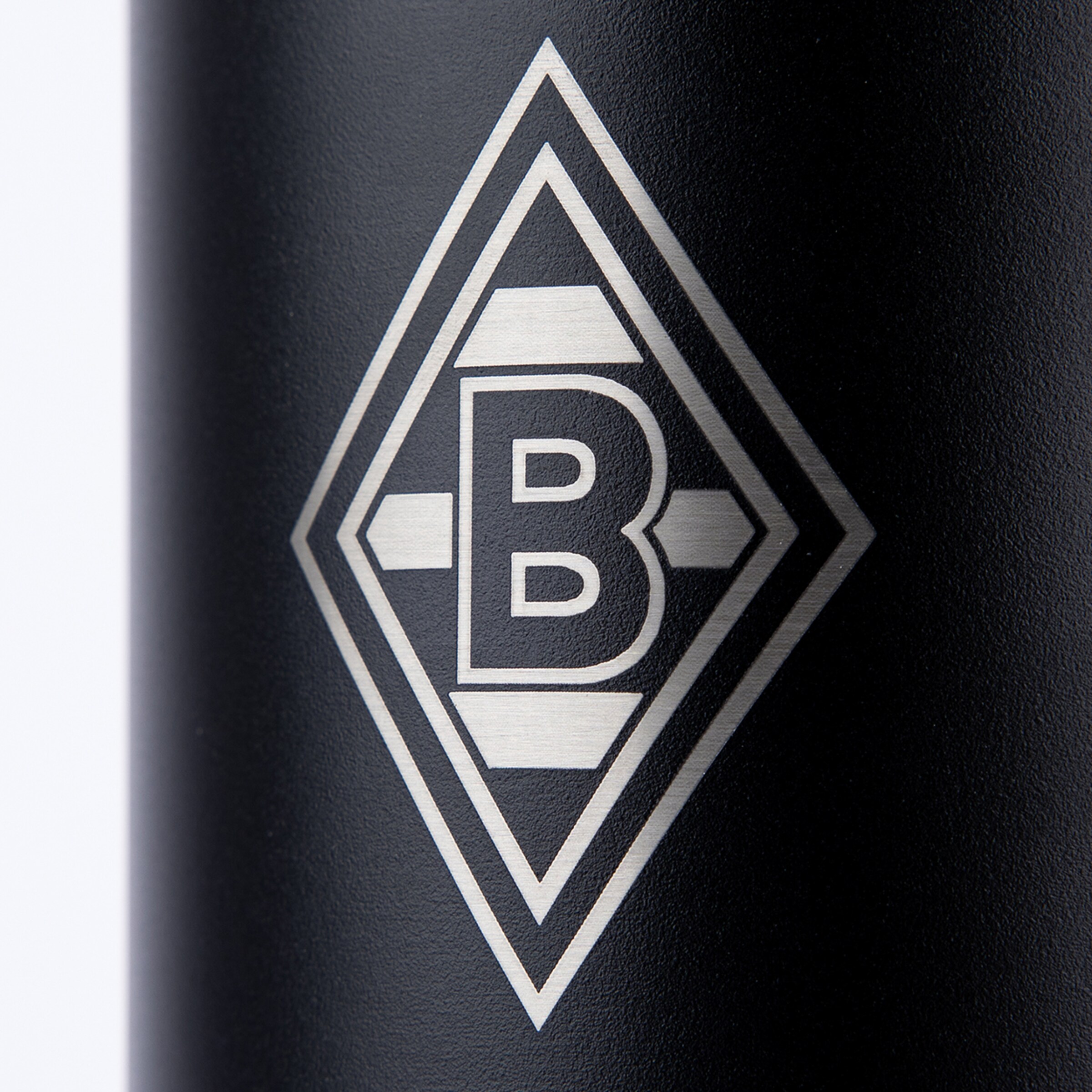 Silbernes Logo von Borussia Mönchengladbach (Raute mit einem B) als Gravur auf einer schwarzen, strukturierten Oberfläche.