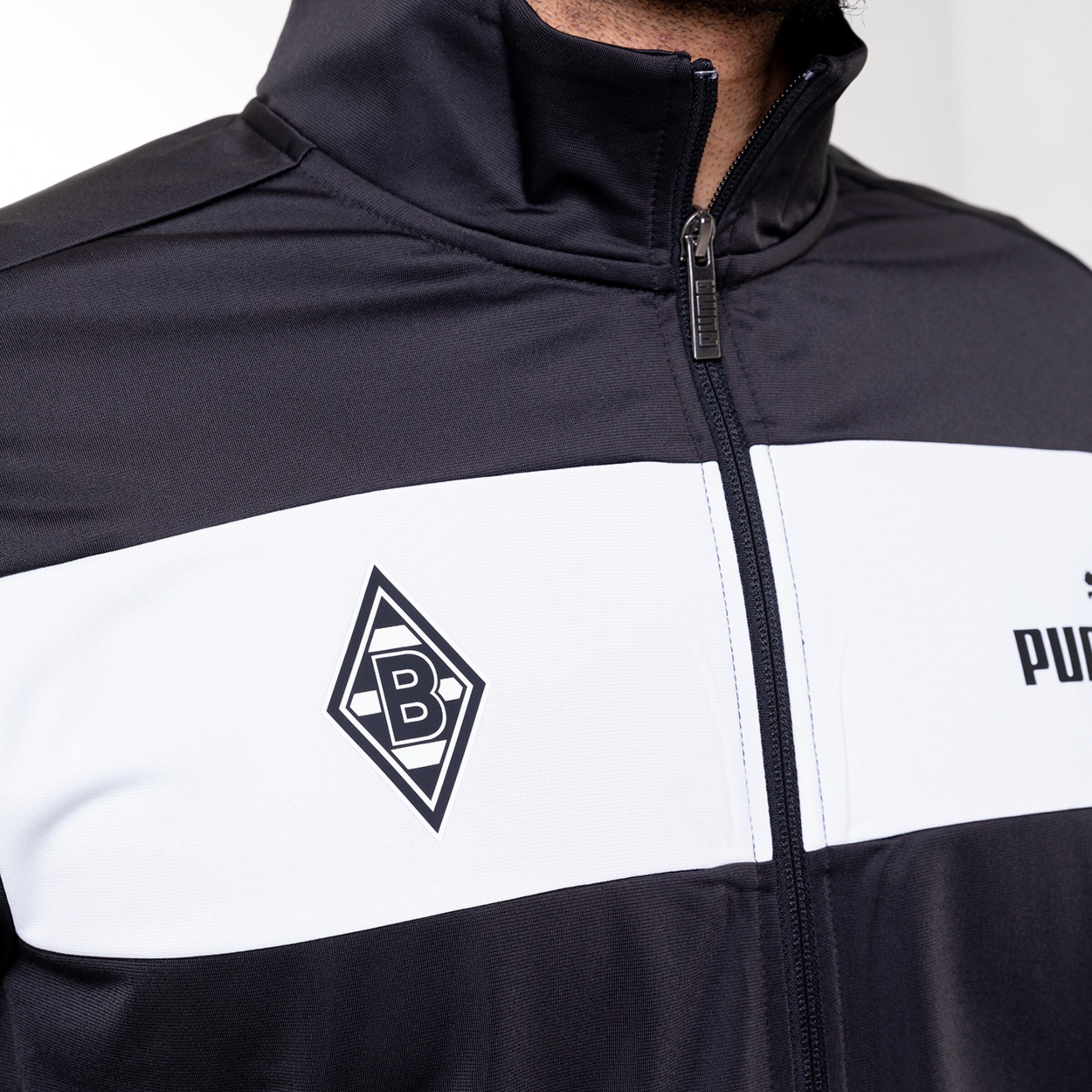 Schwarz-weißer Trainingsanzug mit Borussia Mönchengladbach-Logo auf der Brust.