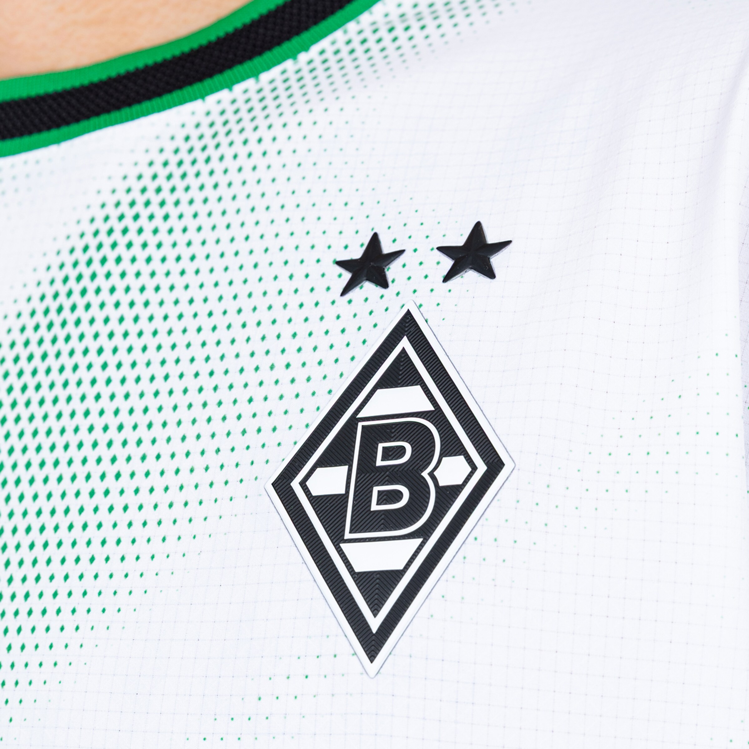 Borussia Mönchengladbach crest with two stars on a white jersey with a green halftone pattern and ribbed collar.
