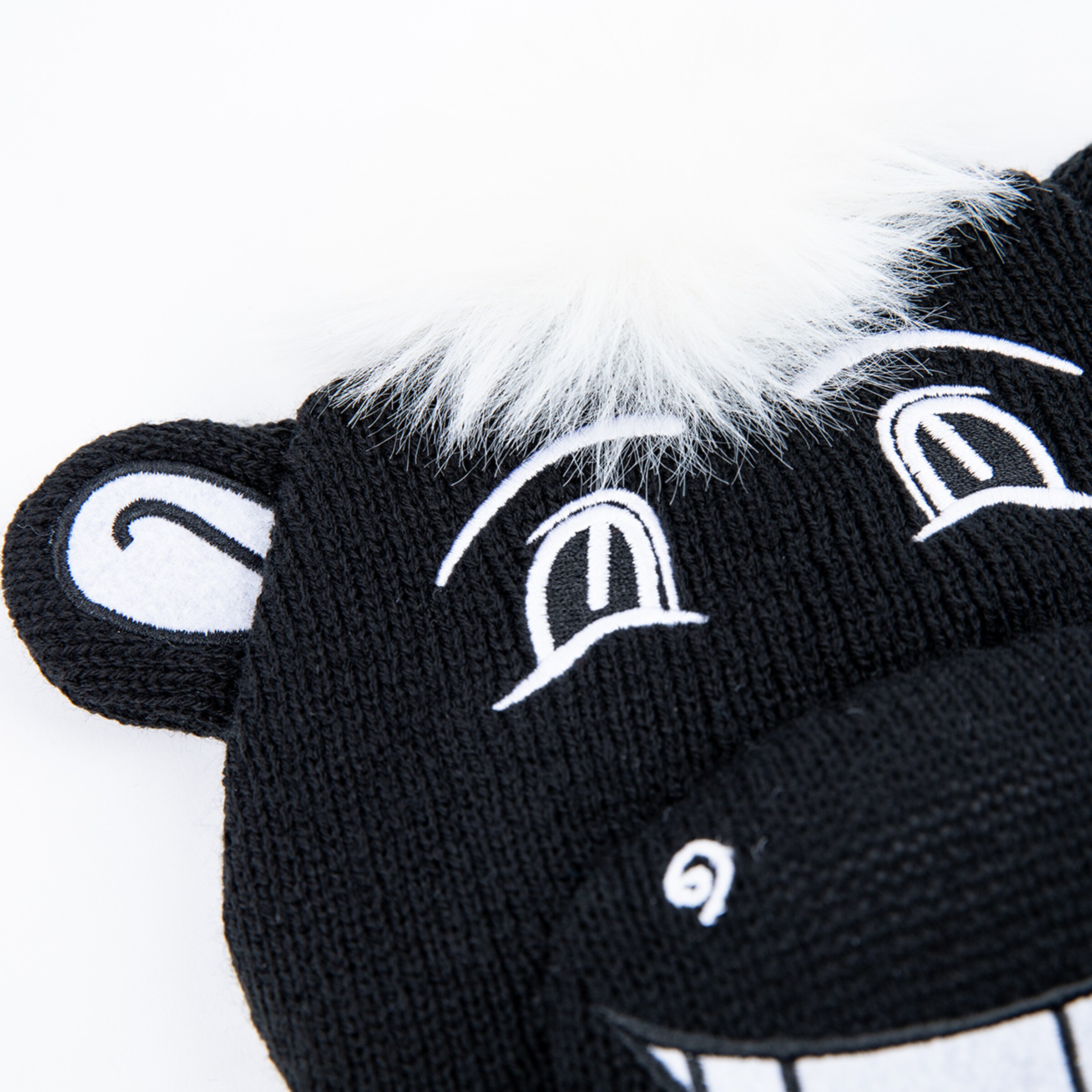 Schwarze Mütze mit Tiergesicht und weißen Details.