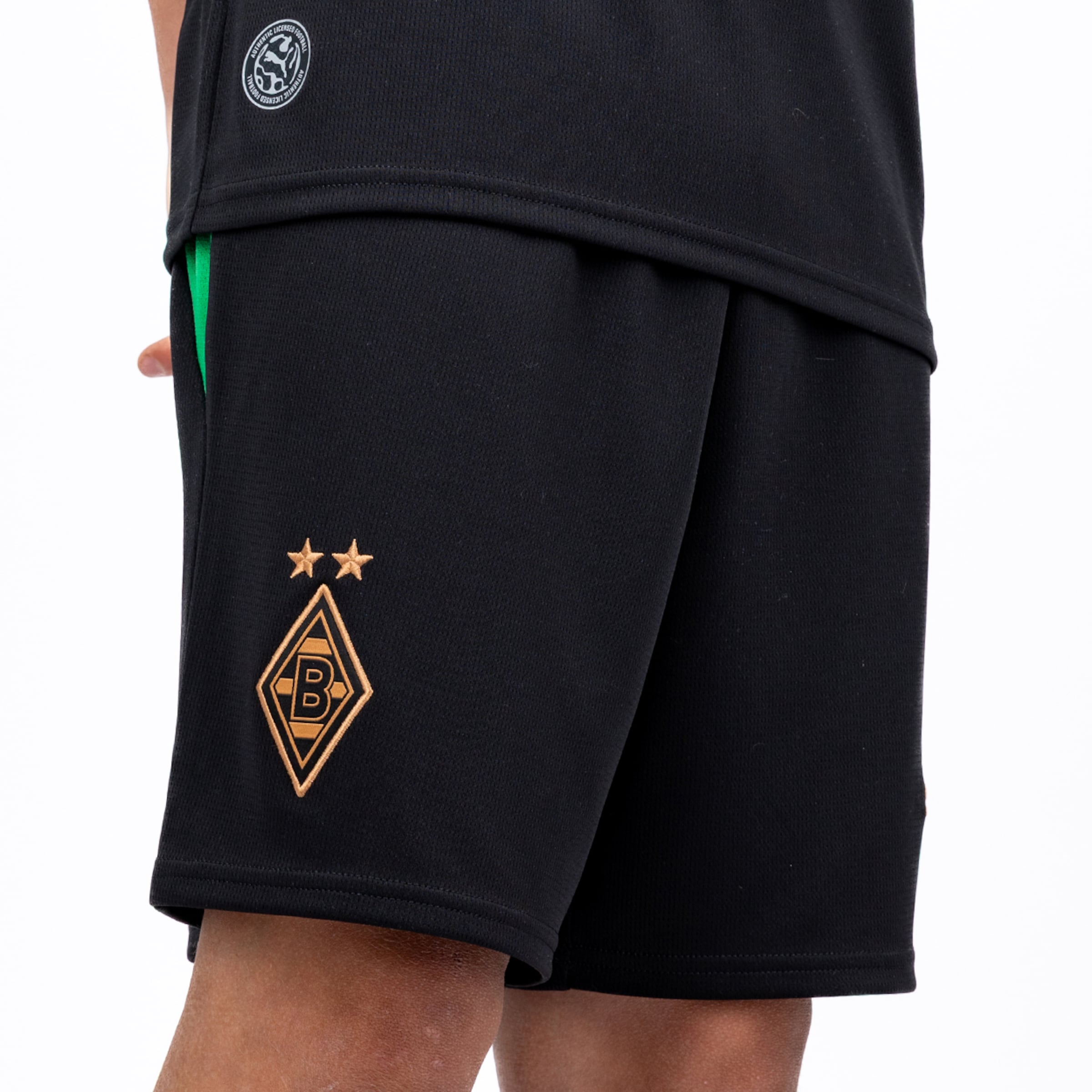 Schwarze Borussia Mönchengladbach Shorts mit goldenem Vereinswappen und zwei Sternen auf dem Hosenbein vor weißem Hintergrund.