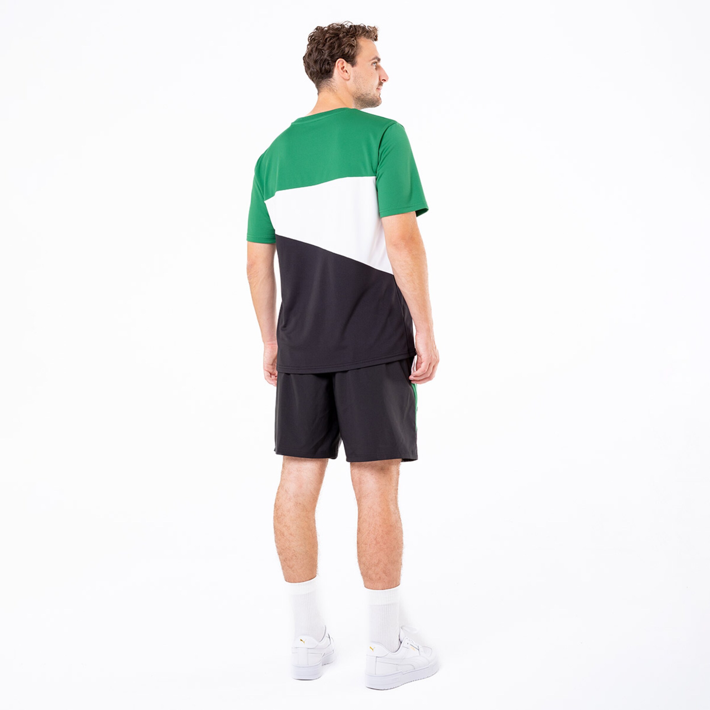 Ein Mann mit einem Sportoutfit aus grünem weißem und schwarzem Stoff steht mit dem Rücken zur Kamera.