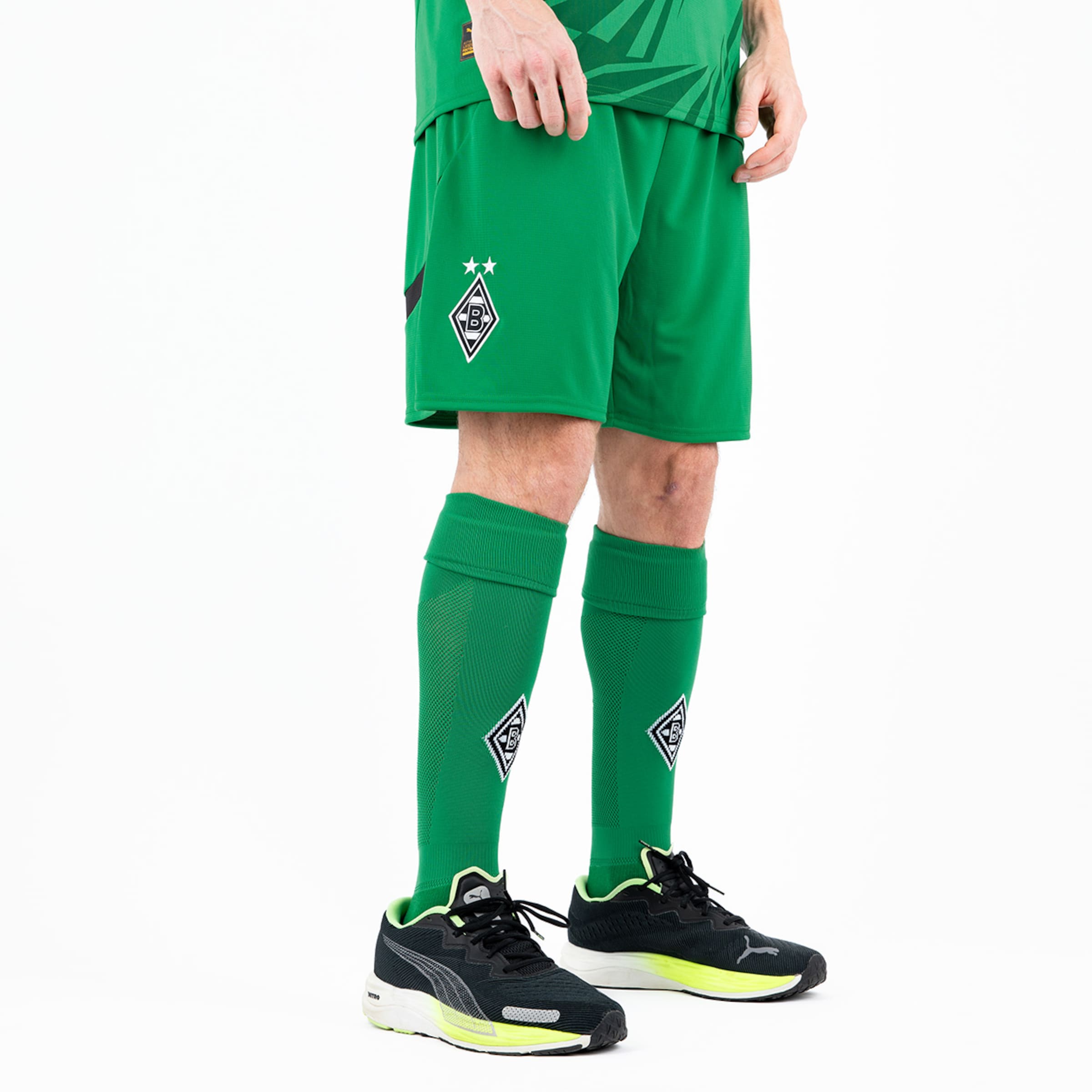 Ein Spieler in einem grünen Borussia Mönchengladbach-Trikot und Shorts steht in Sportchuhen.
