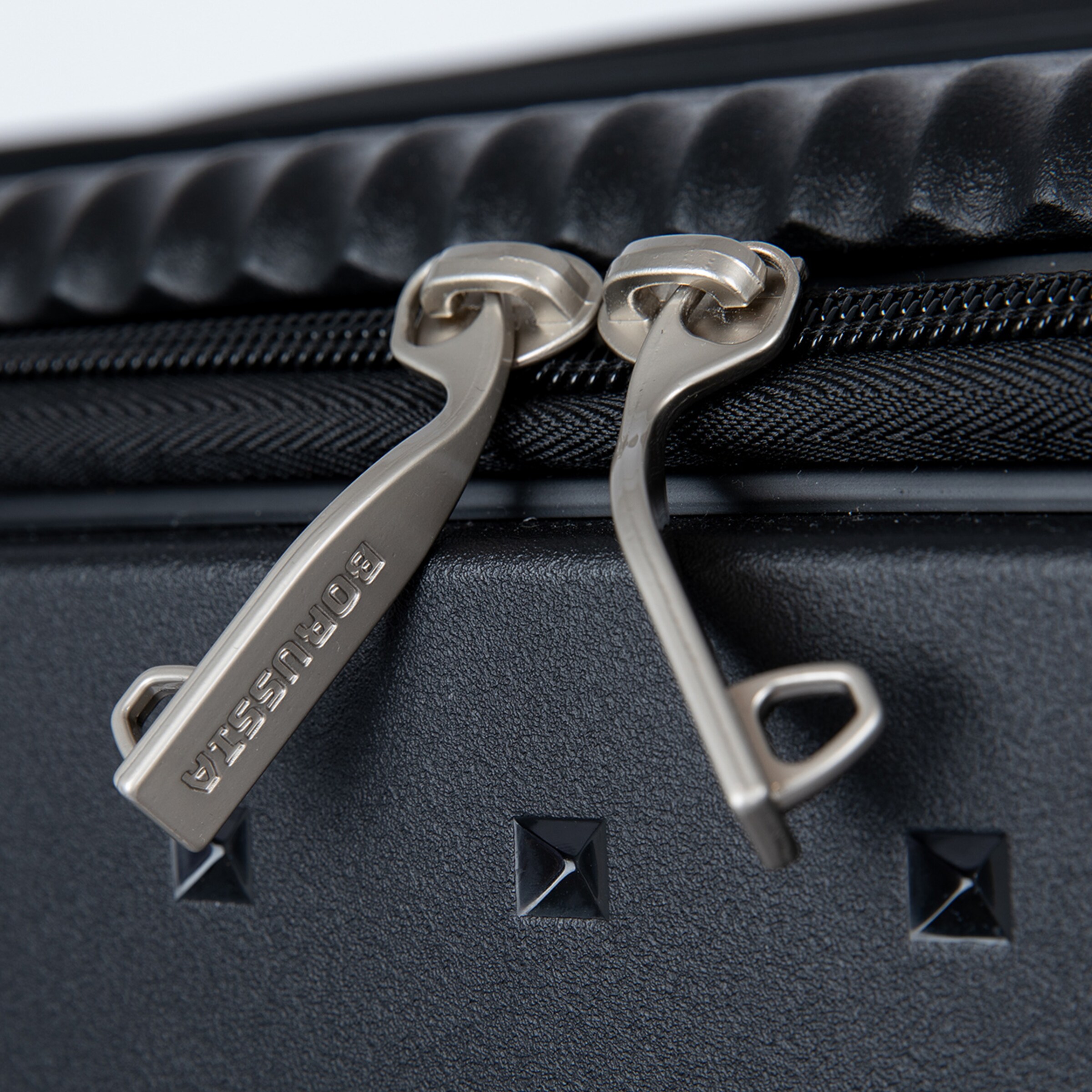Zwei silberne Reißverschlussmarken an einem schwarzen Koffer.