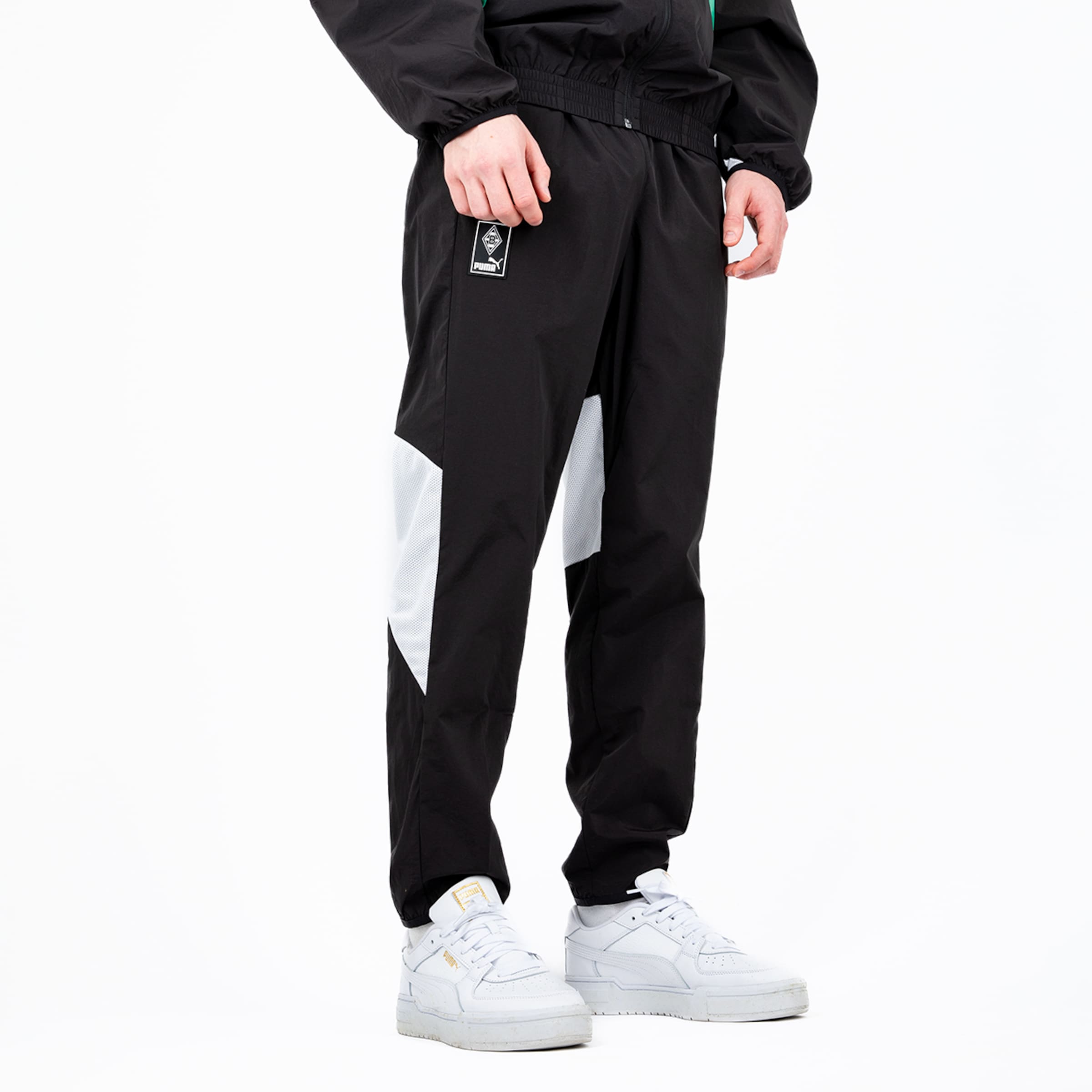 Schwarze Sporthose mit weißen Details und elastischem Bund kombiniert mit weißen sneakers.