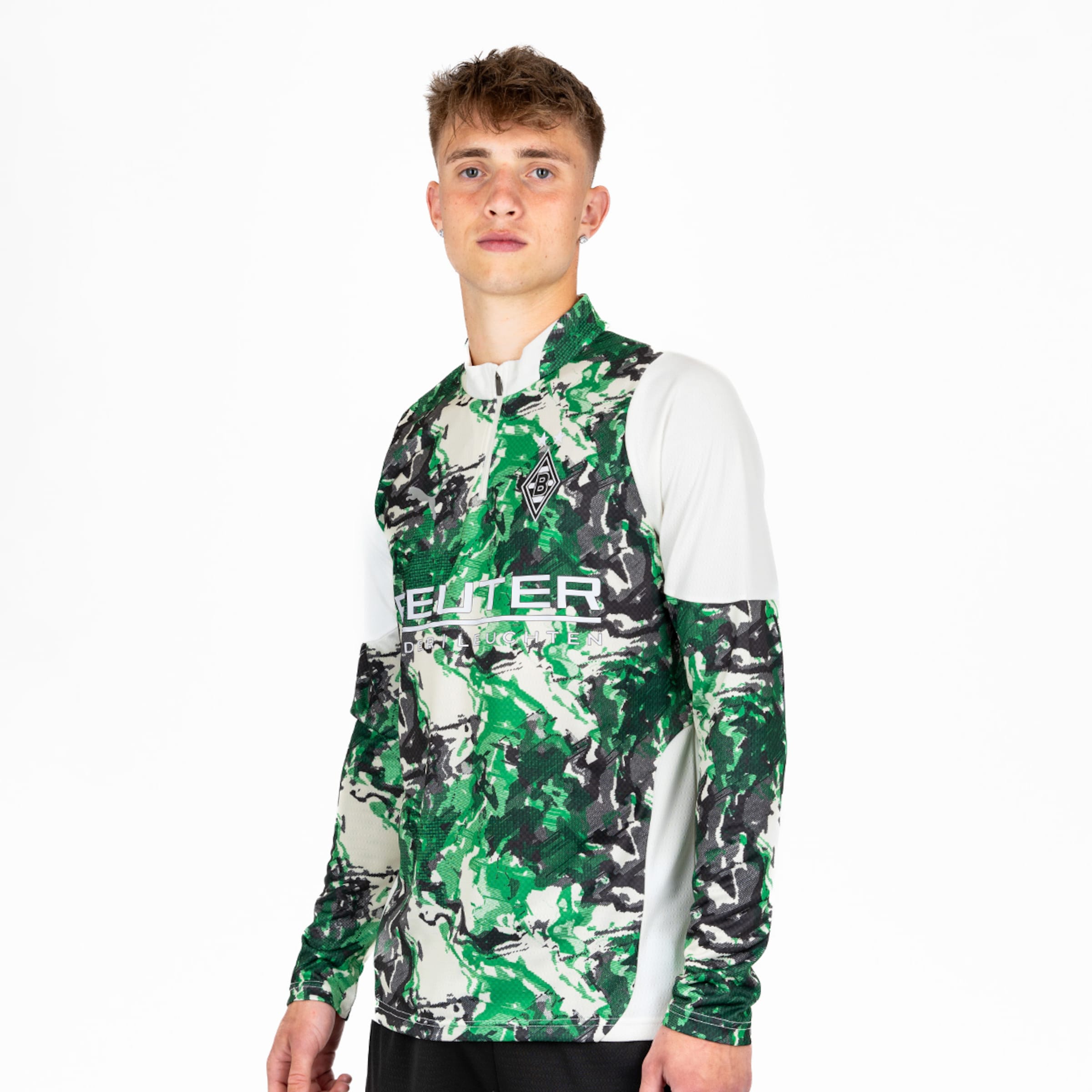 Ein junger Mann trägt ein langärmeliges Trikot mit einem modernen camouflierten Design in grün schwarz und weiß.