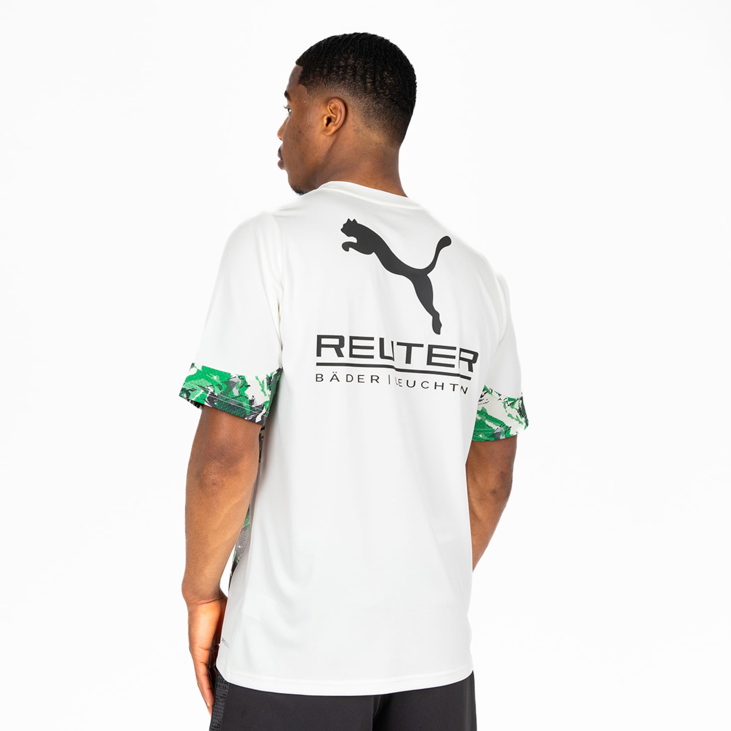 Rückansicht eines Mannes in weißem Puma-Shirt mit Logo, REUTER-Schriftzug und grün gemusterten Ärmeln vor weißem Hintergrund.