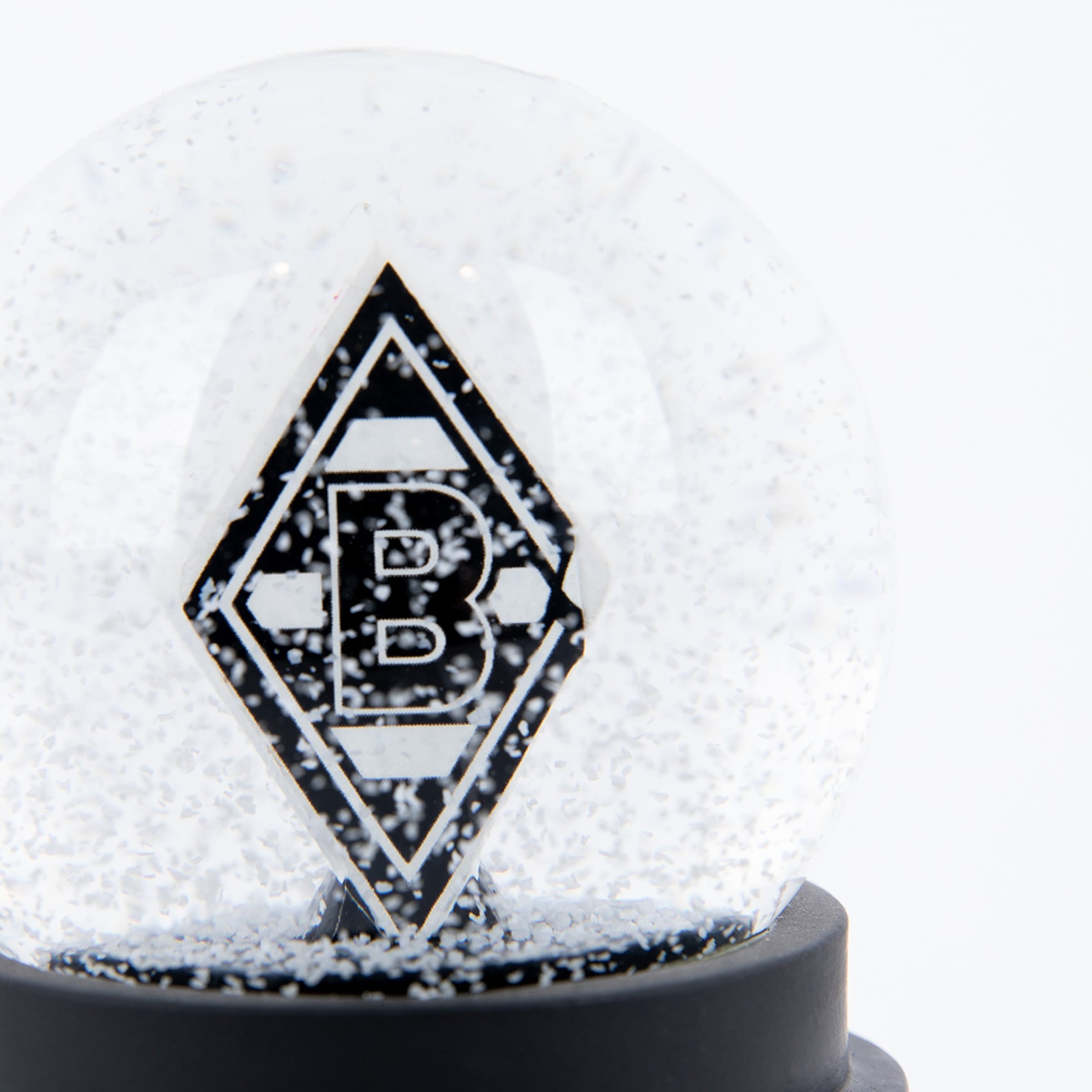 Schneekugel mit dem schwarz-weißen Rauten-Logo von Borussia Mönchengladbach auf einem schwarzen Sockel vor weißem Hintergrund.