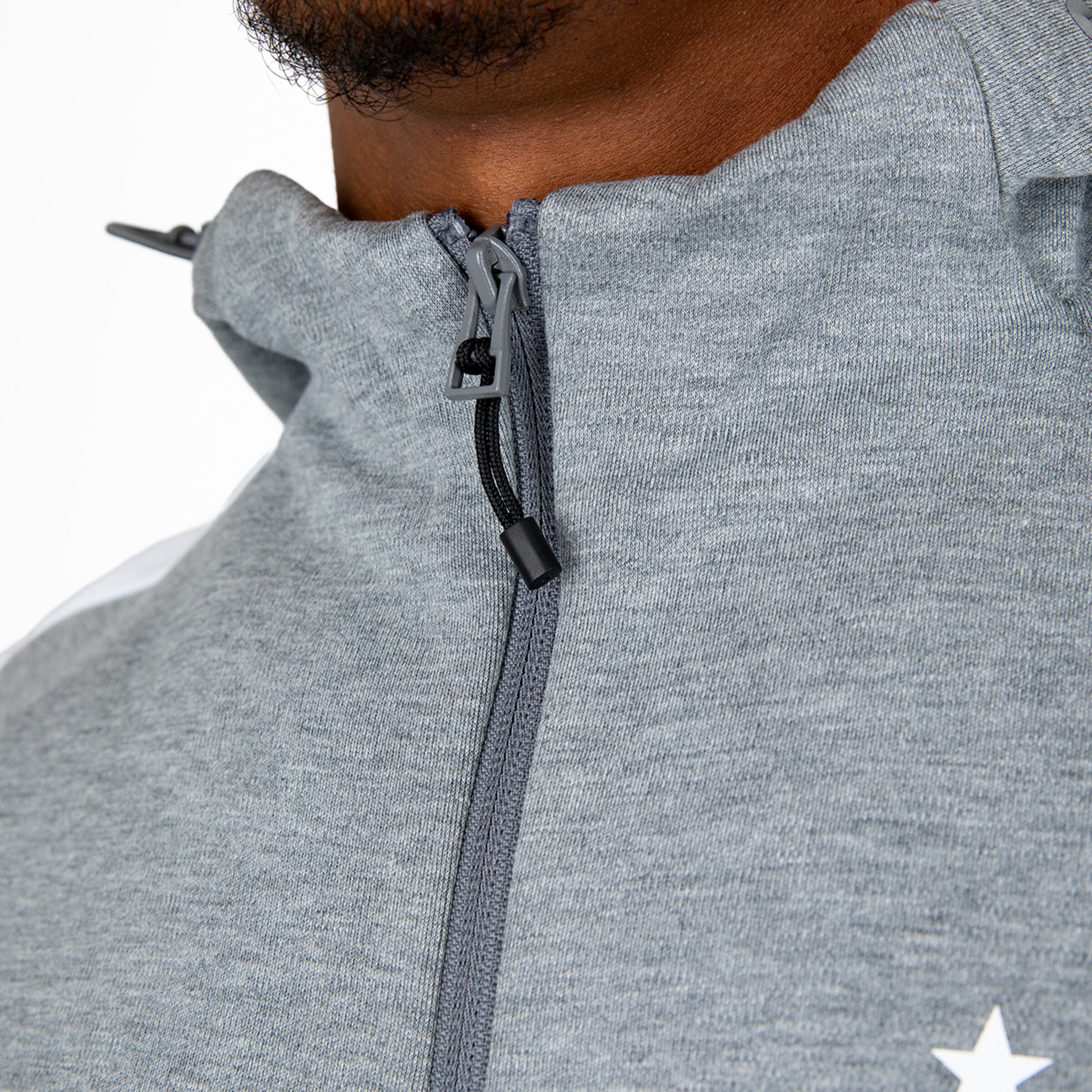 Nahaufnahme eines grauen Sportoberteils mit einem Reißverschluss.