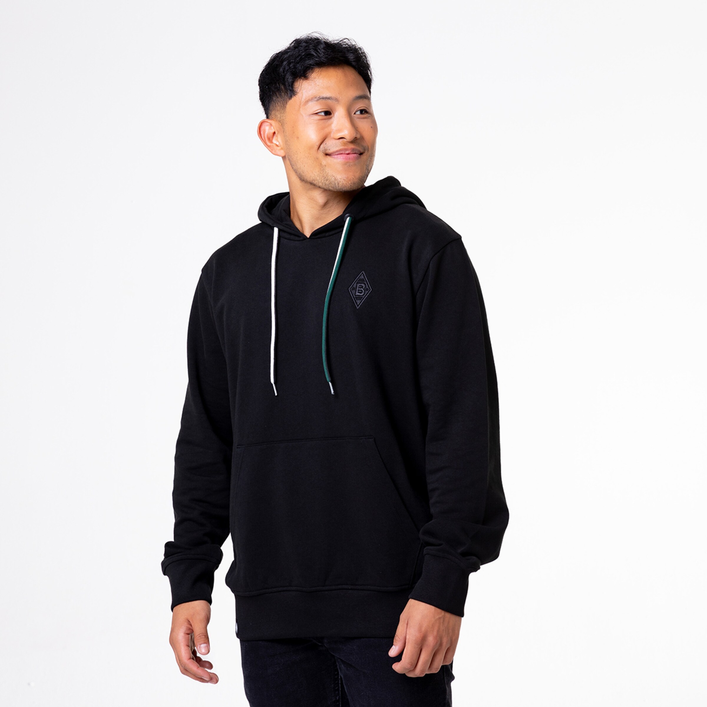 Mann trägt schwarzen Hoodie mit kleinem Logo auf der Brust.