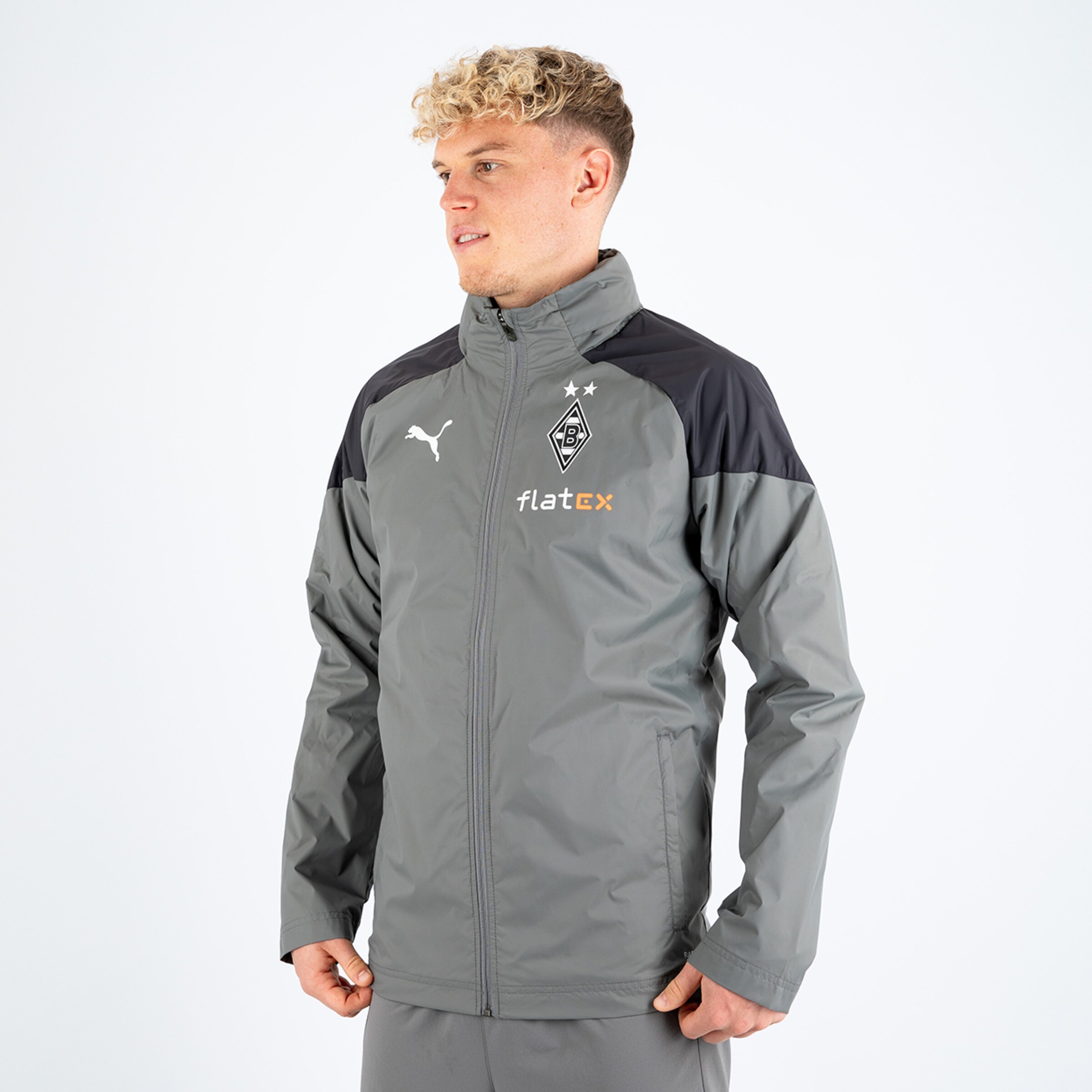 Mann in grauer Trainingsjacke mit schwarzem oberen Bereich und Borussia Mönchengladbach-Logo.