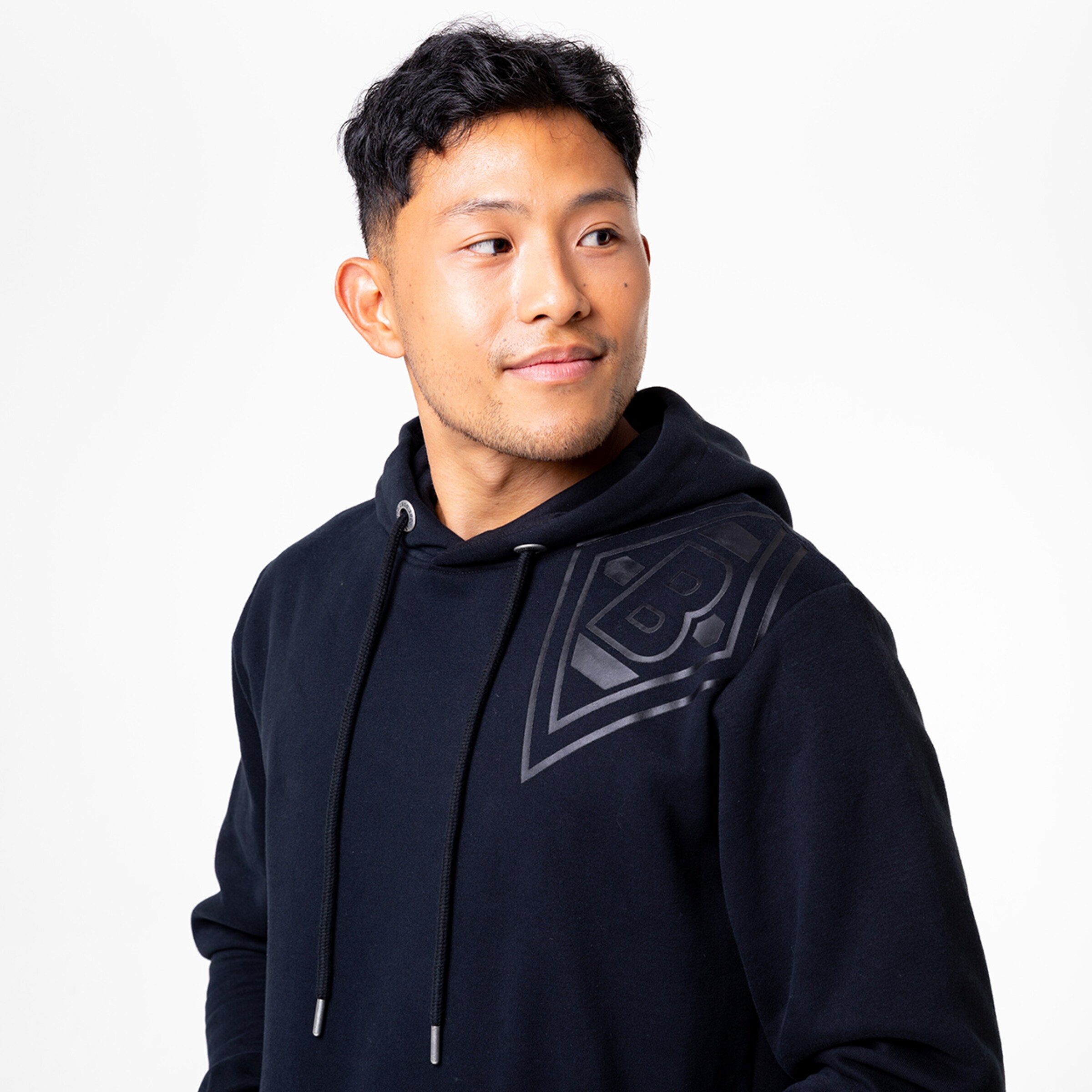 Mann trägt eine schwarze Kapuzenjacke mit grafischem Design.