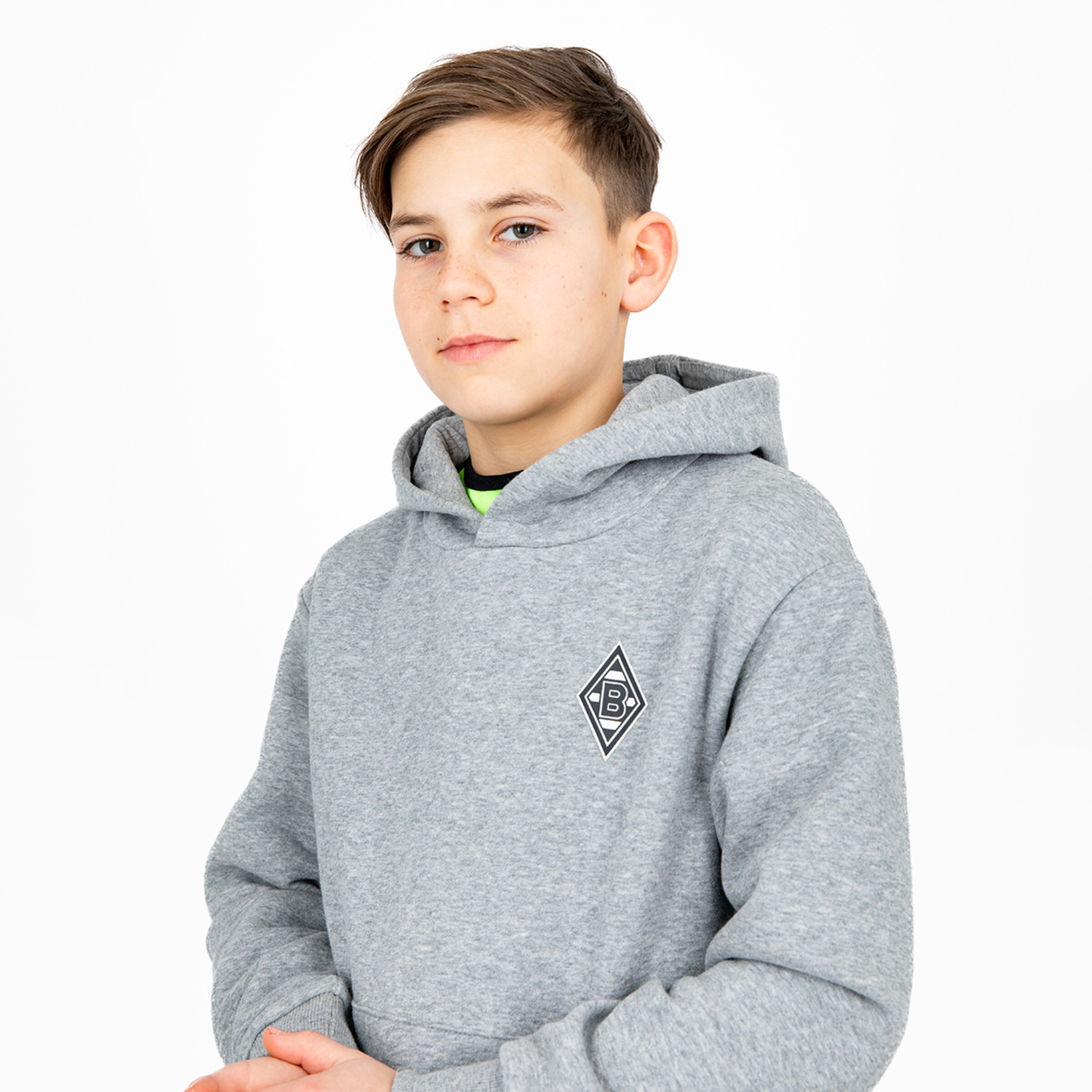 Ein Junge in einem grauen Hoodie mit Borussia Mönchengladbach Logo schaut ernst.