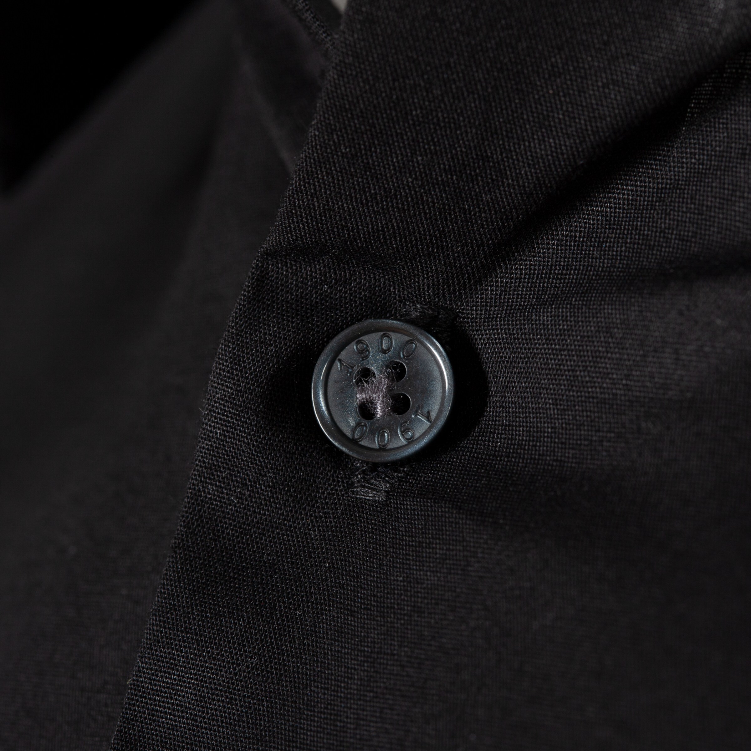 Schwarzer Knopf an einem schwarzen Kleidungsstück.