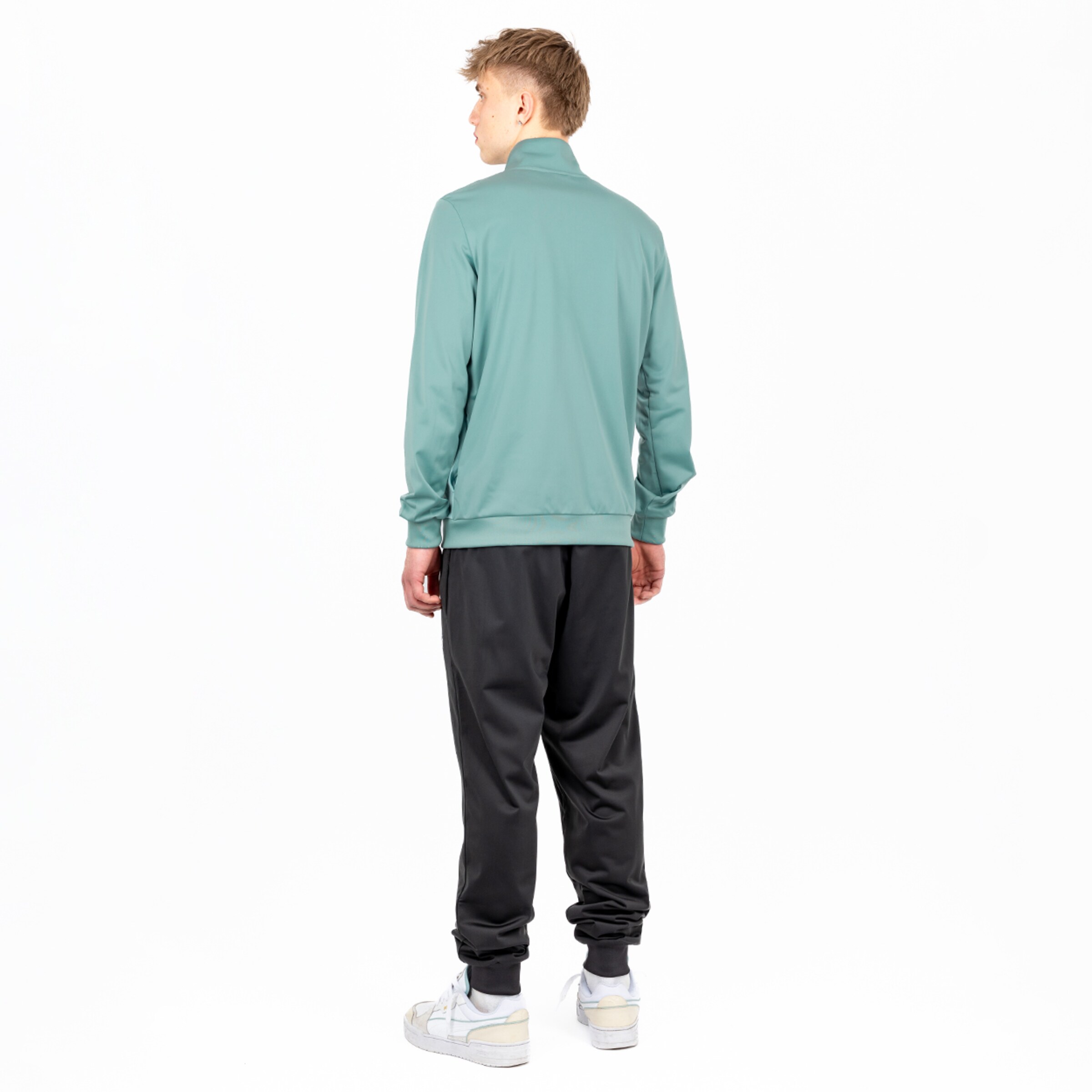 Back view of a man wearing a mint green top and black sweatpants.