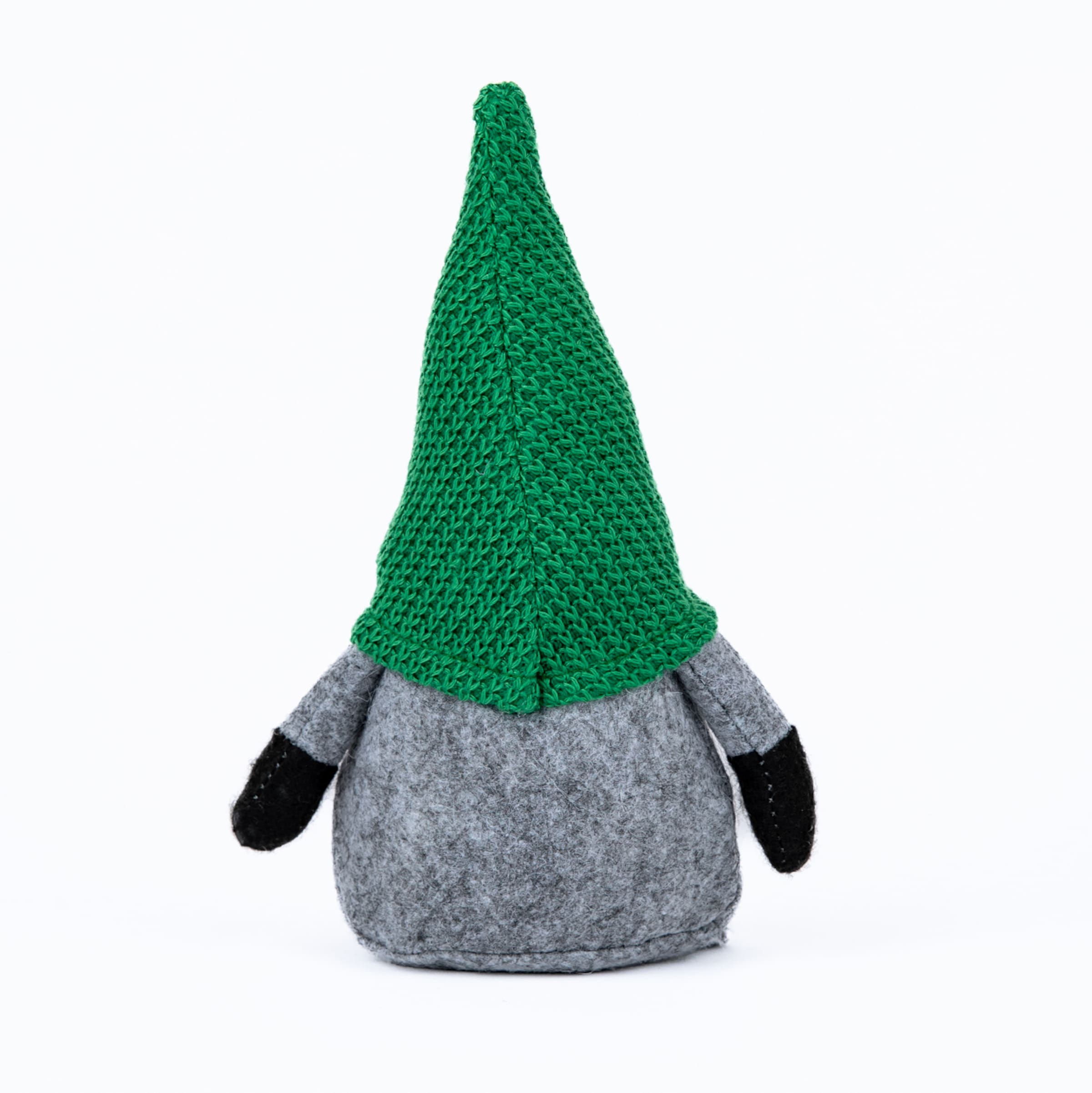 Rückansicht eines kleinen Wichtels mit hoher grüner Strickmütze, grauem Filzkörper und schwarzen Händen vor weißem Hintergrund.