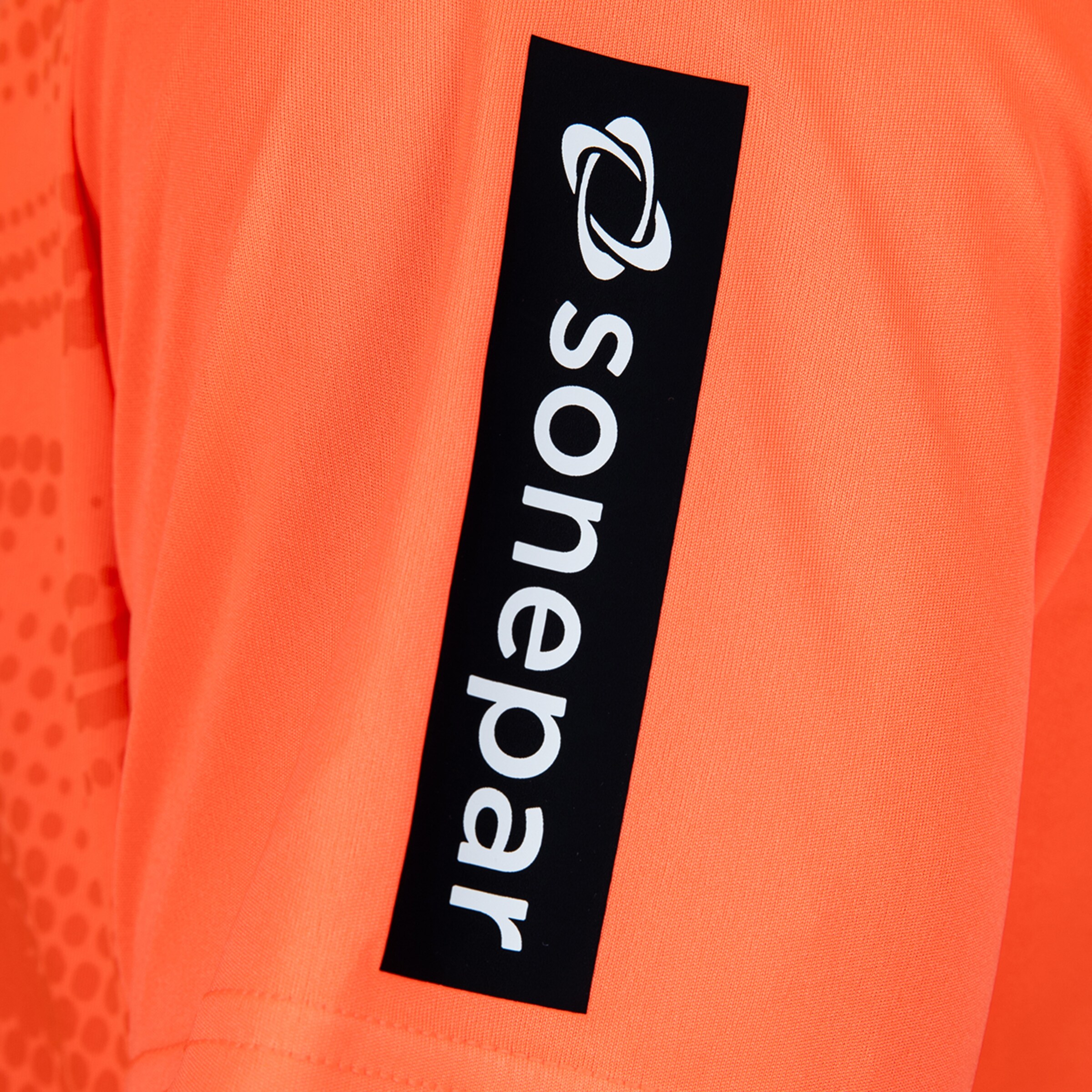 Close-up of an orange jersey sleeve featuring the Sonepar logo and text in white on a vertical black patch.