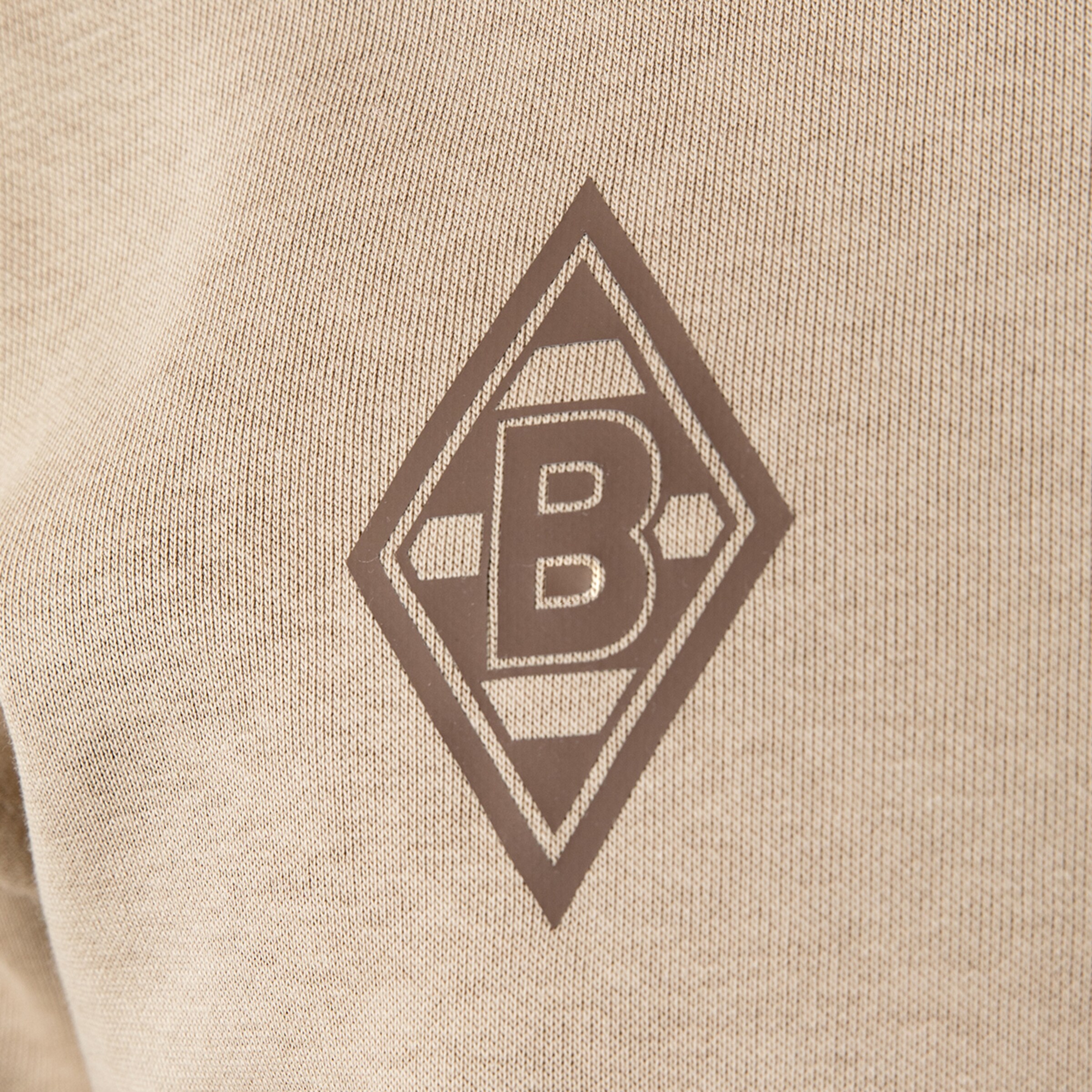 Brown Borussia Mönchengladbach logo in diamond shape on beige fabric.
