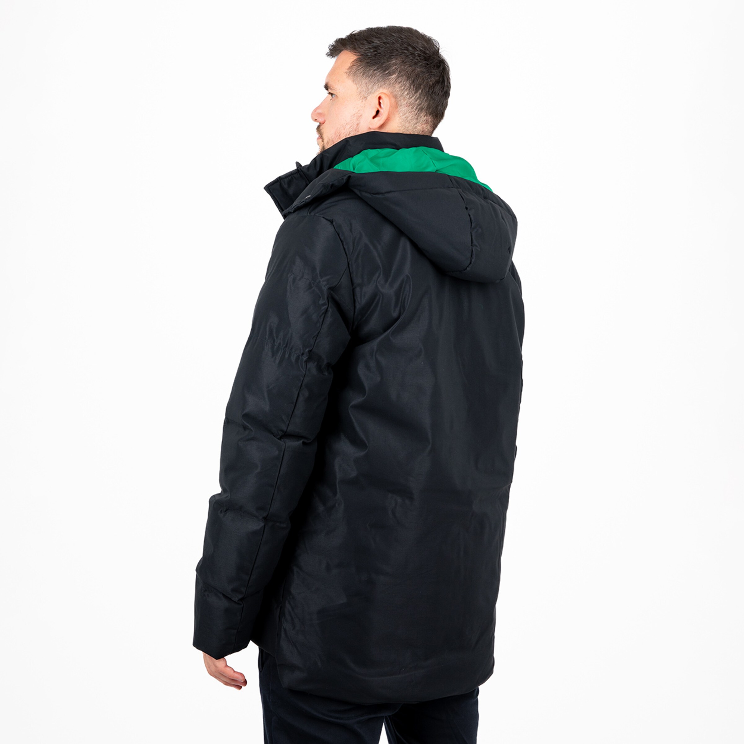 Mann mit schwarzer Jacke von hinten grüne Kapuze sichtbar.