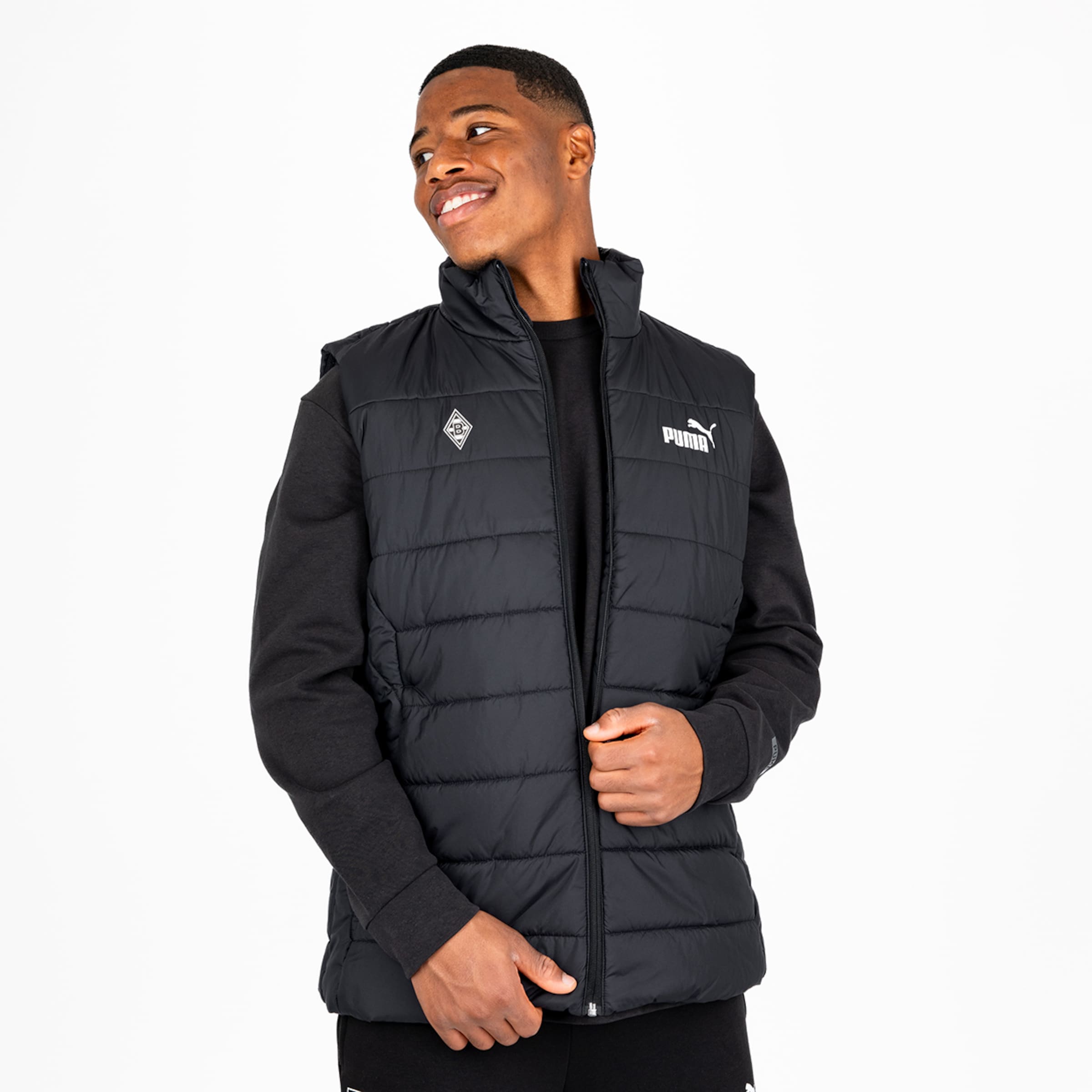 Man wearing a black padded PUMA vest featuring the Borussia Mönchengladbach emblem.