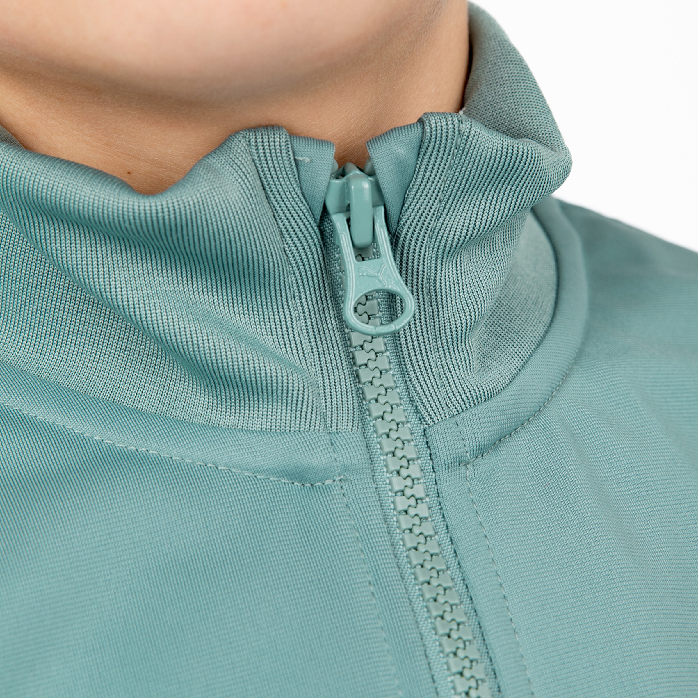 Nahaufnahme eines Reißverschlusses an einem hellblauen Kleidungsstück mit einem hohen Kragen.